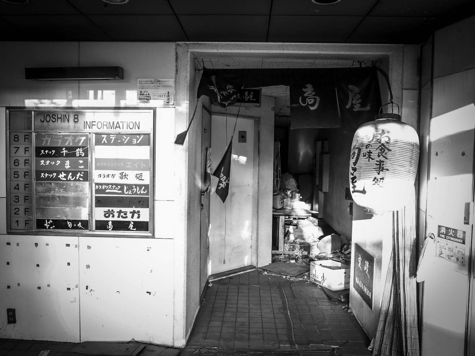 Scena di un corridoio poco illuminato con una porta e insegne