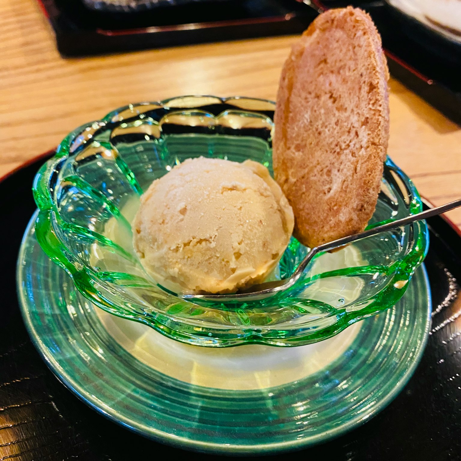 Vanilla ice cream served in a green glass dish with a cookie