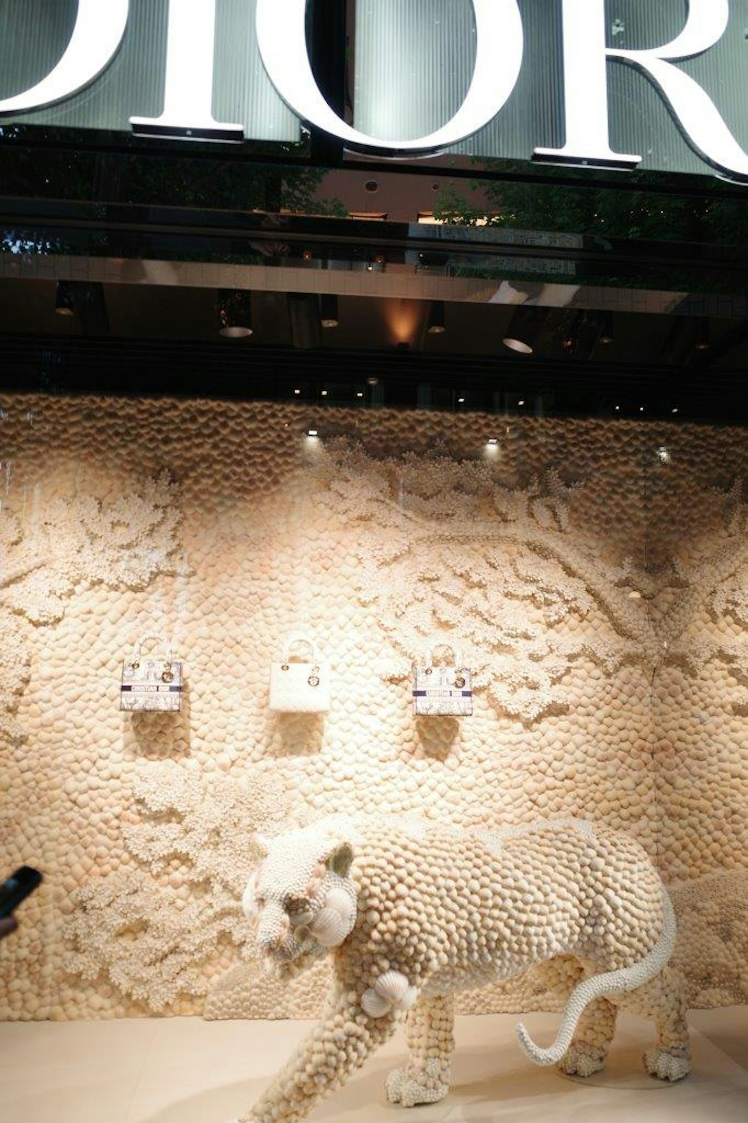 Dior-Schaufenster mit einer weißen Leopardskulptur und einem naturthemen Hintergrund