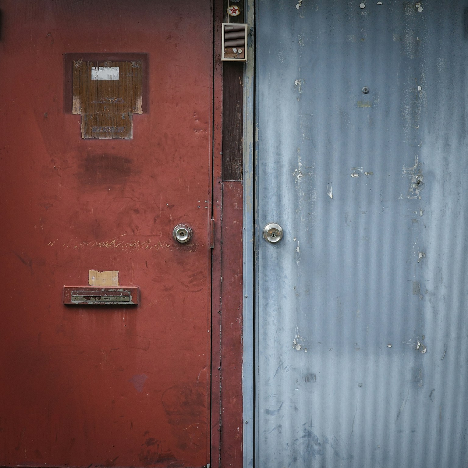 A red door and a blue door side by side with weathered textures