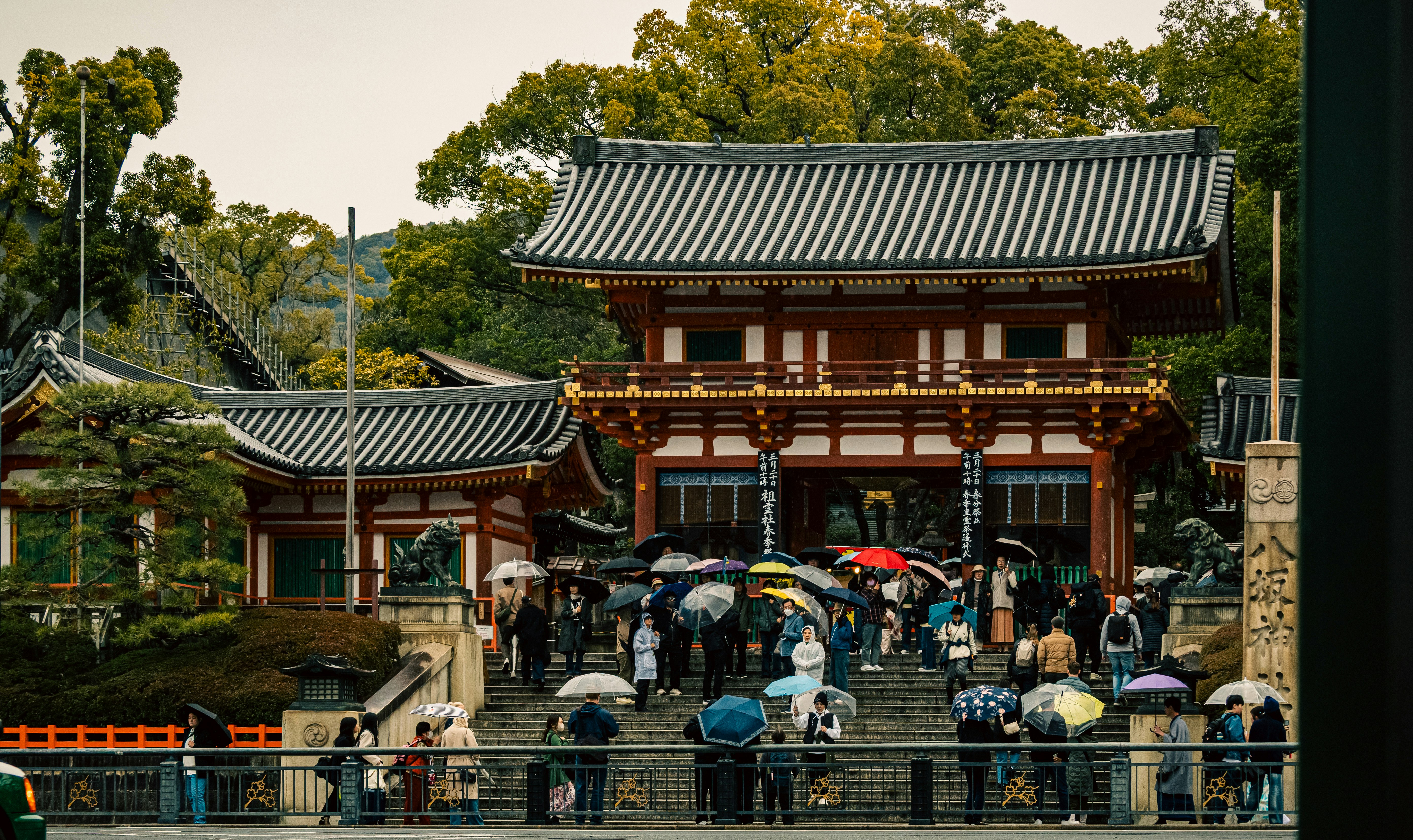 石段のある寺院の門と参拝者、バイクが並ぶ参道