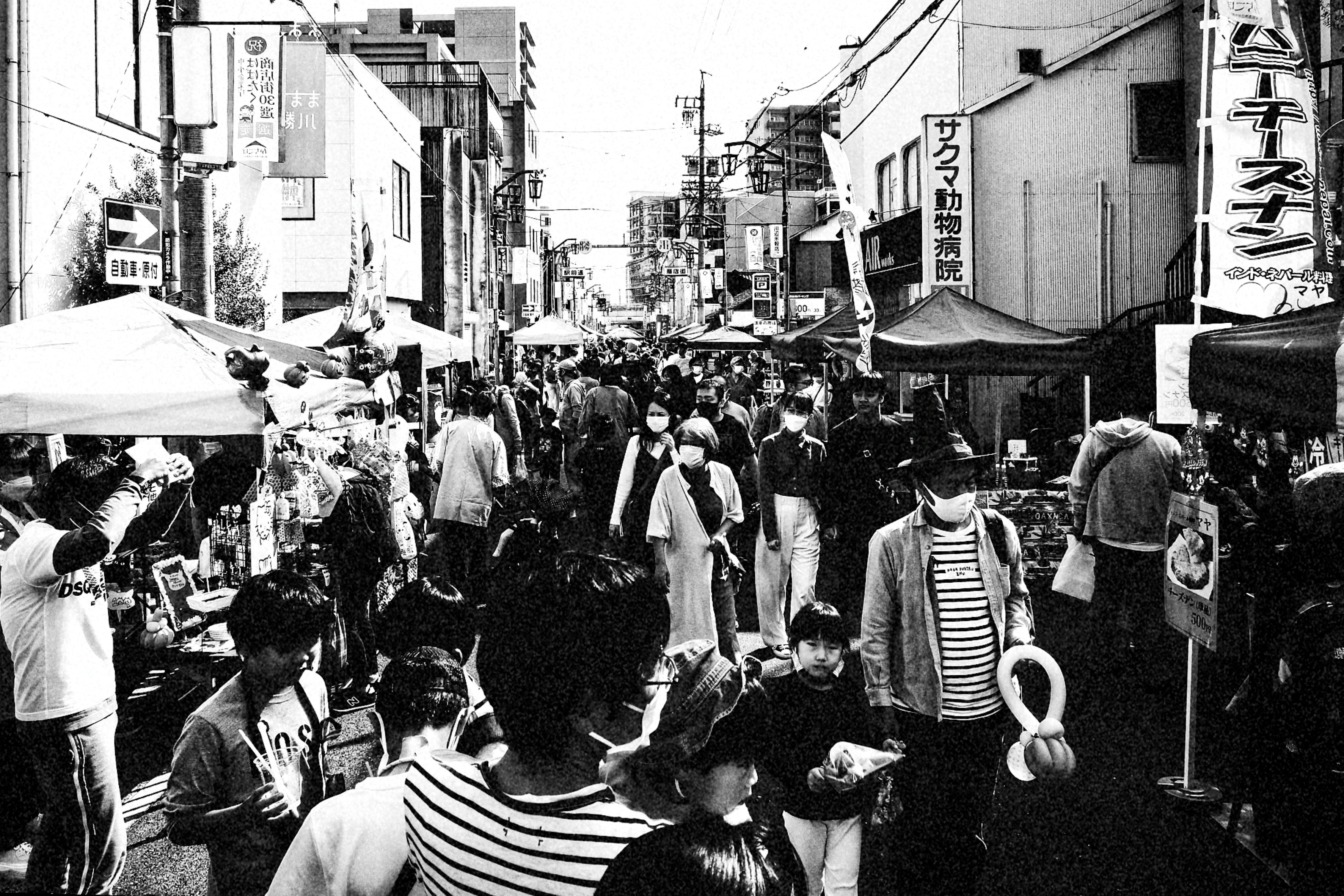 路地の出店が並ぶ町内祭りのモノクロスナップ