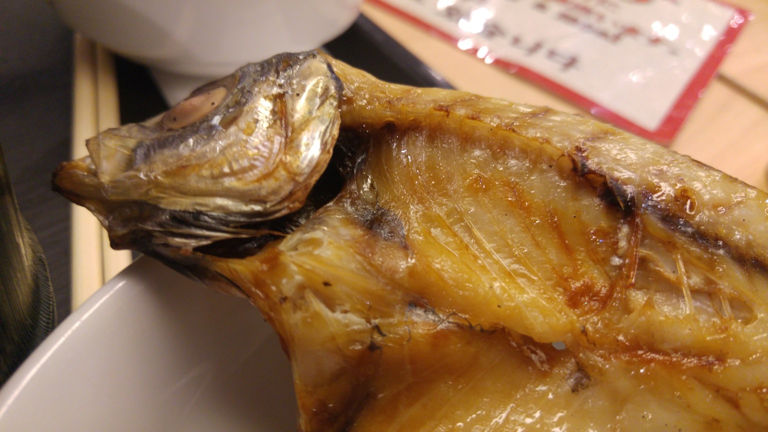 Close-up ikan bakar menampilkan kepala dan daging yang lembab