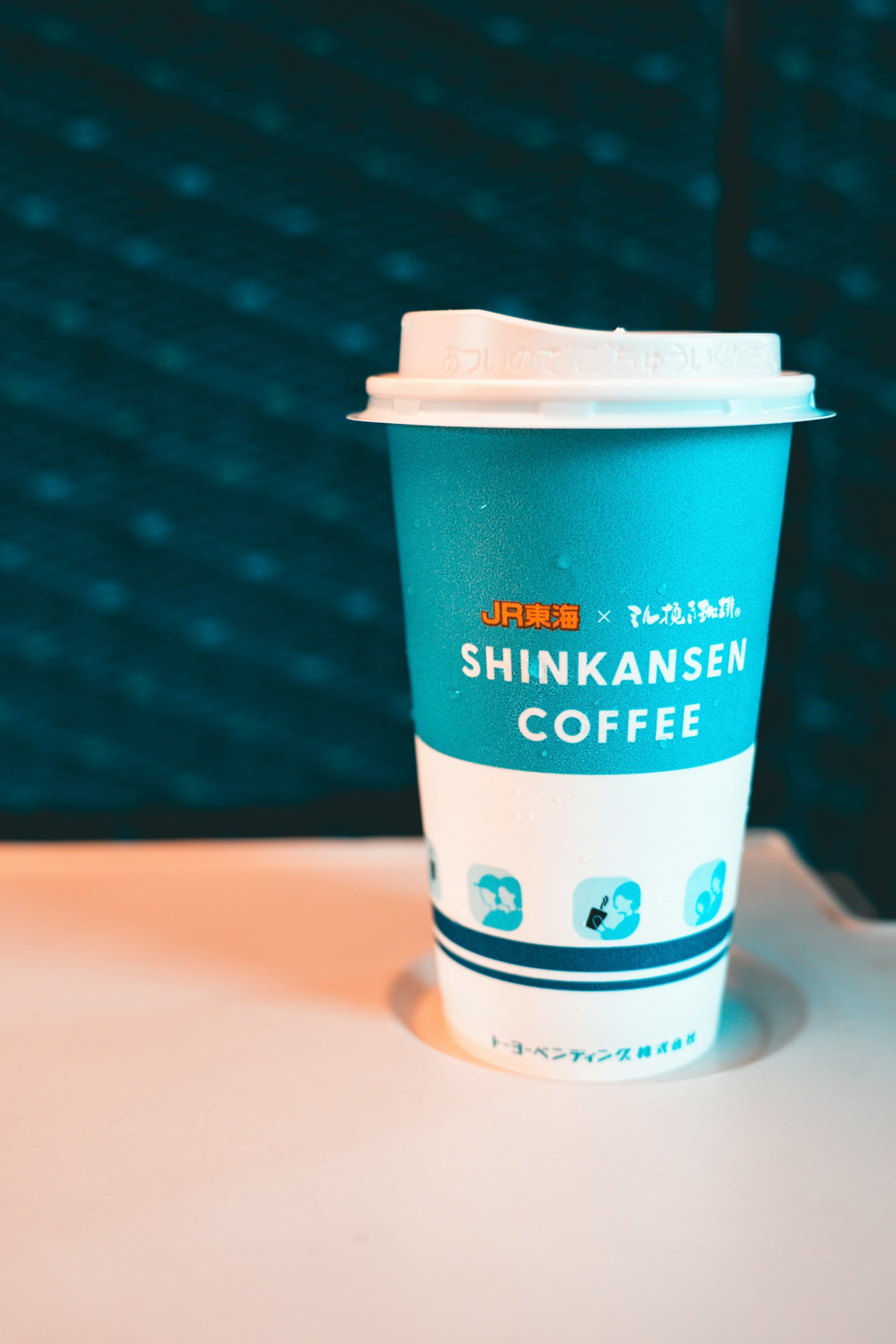 ถ้วยสีน้ำเงินที่มีกาแฟชินคันเซนและฝาปิดสีขาว