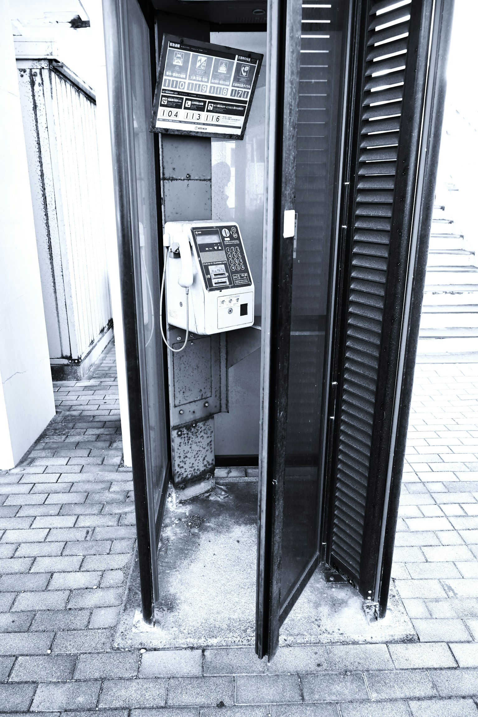 Image en noir et blanc d'une cabine téléphonique vide