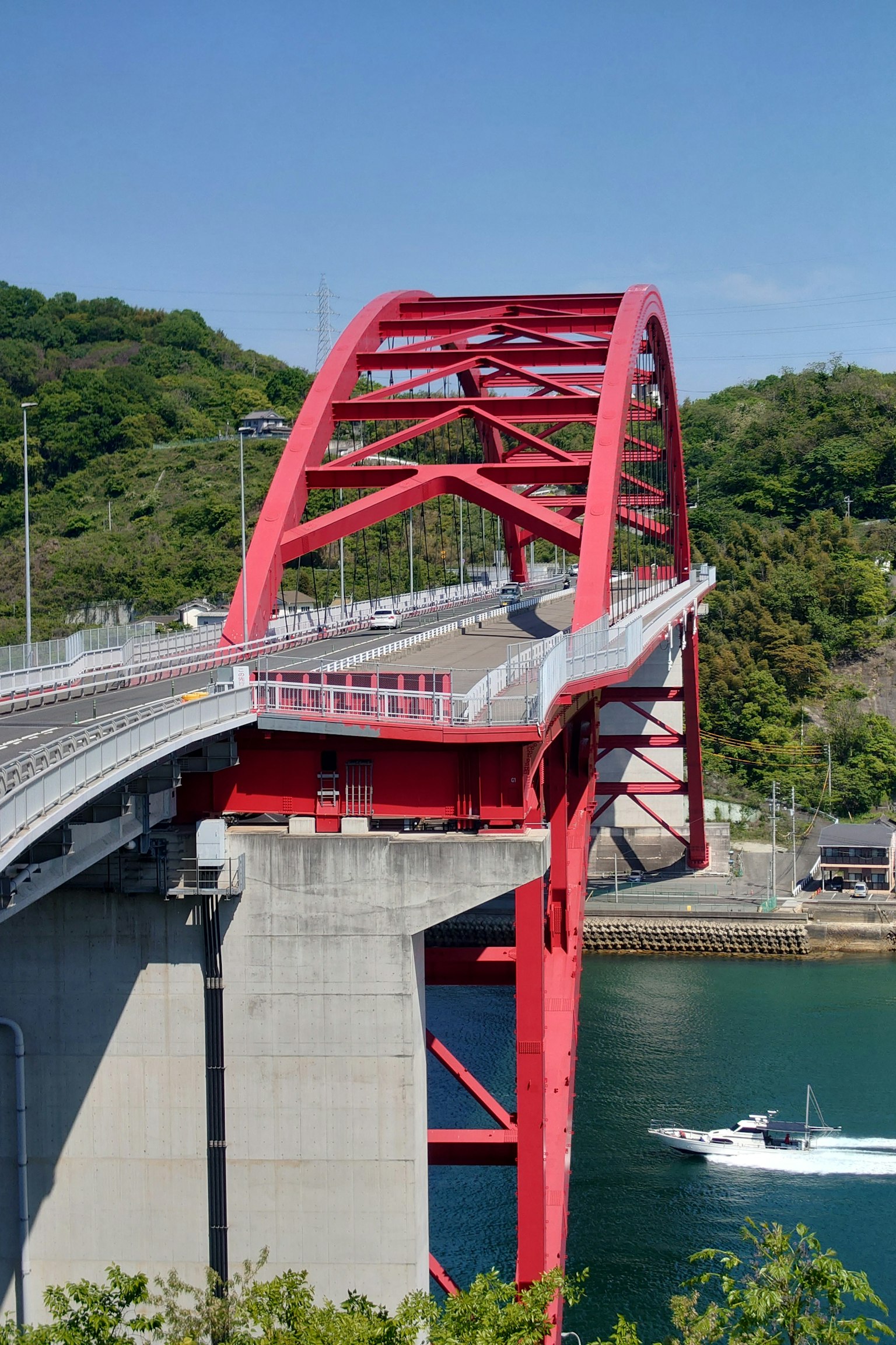 Red arch bridge with surrounding greenery and blue water