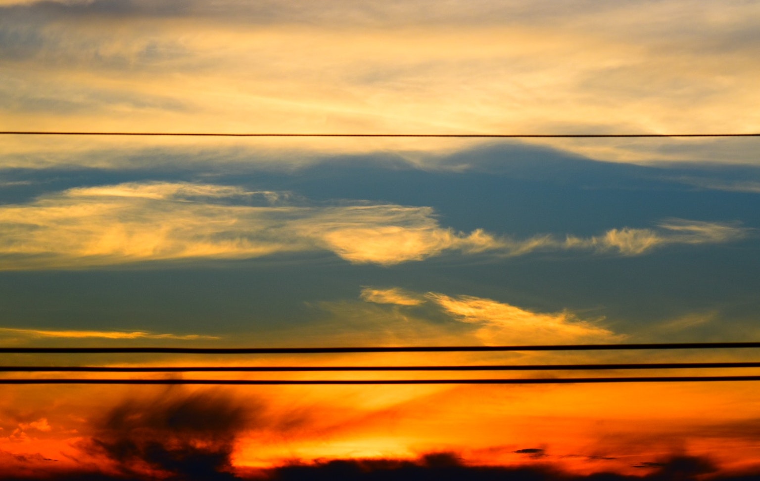 Schöner Sonnenuntergangshimmel mit orange und blauen Farbtönen und Stromleitungen