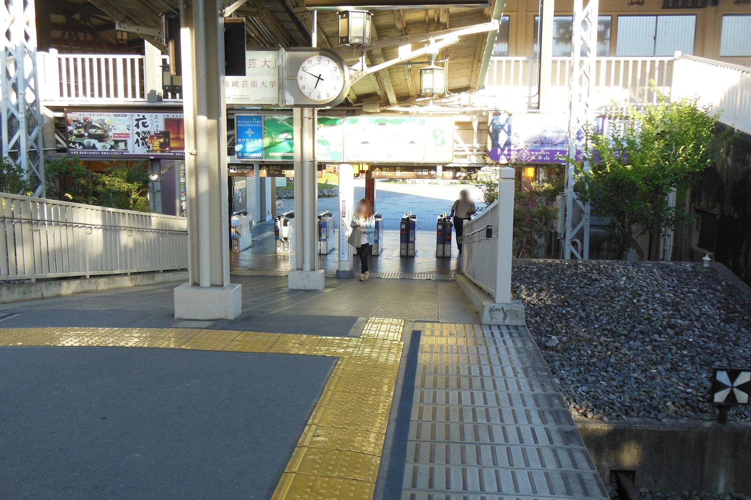Vista de una plataforma de estación de tren con un reloj y personas