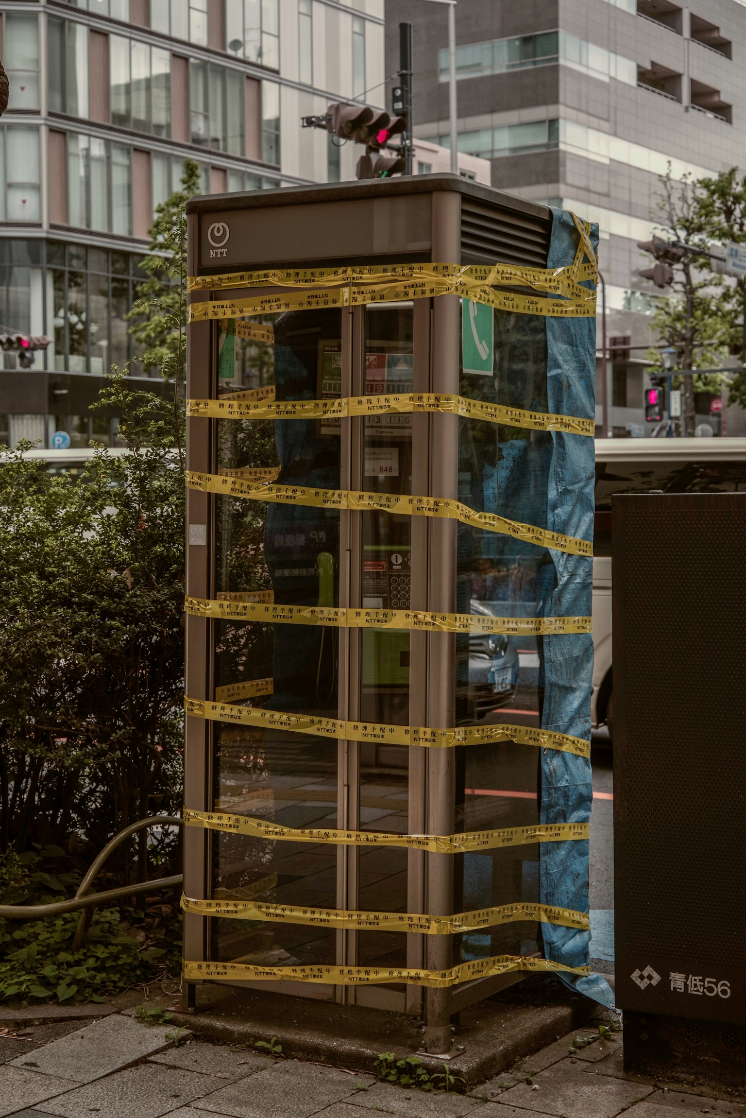 城市环境中被蓝色塑料和黄色胶带覆盖的电话亭