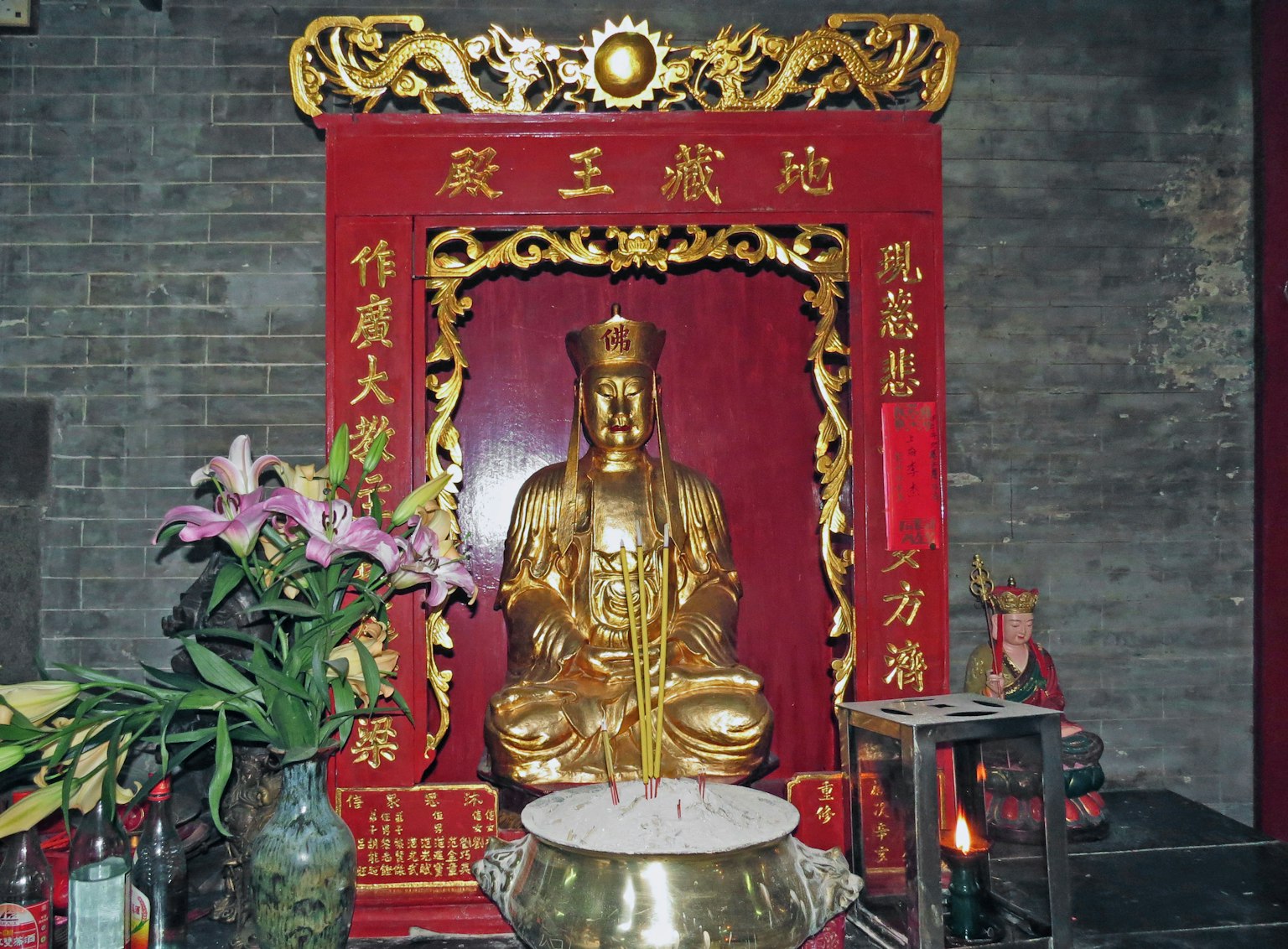 红色祭坛上的金色雕像，配有鲜花和香