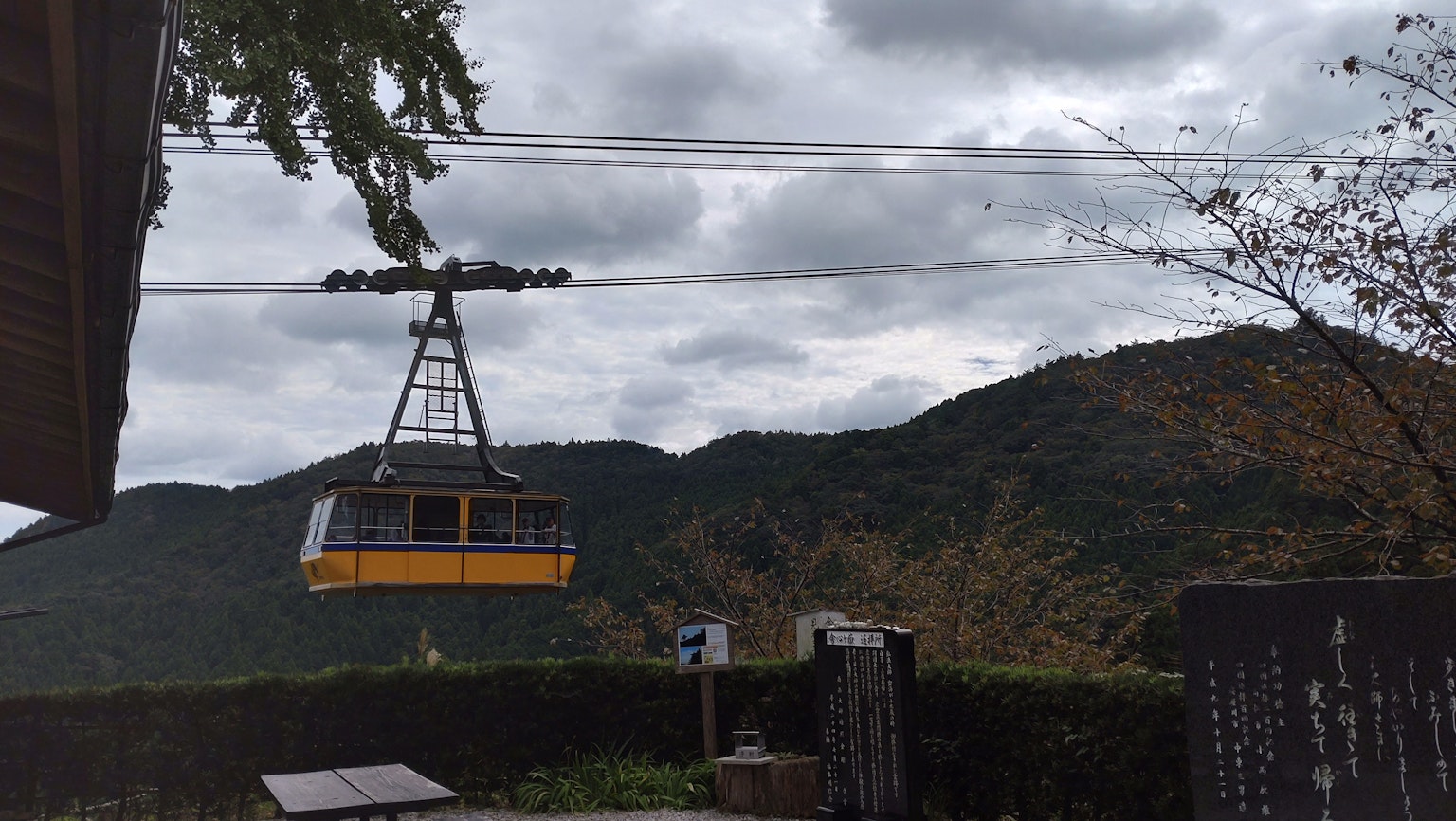 A yellow gondola lift heading up a mountain with cloudy skies