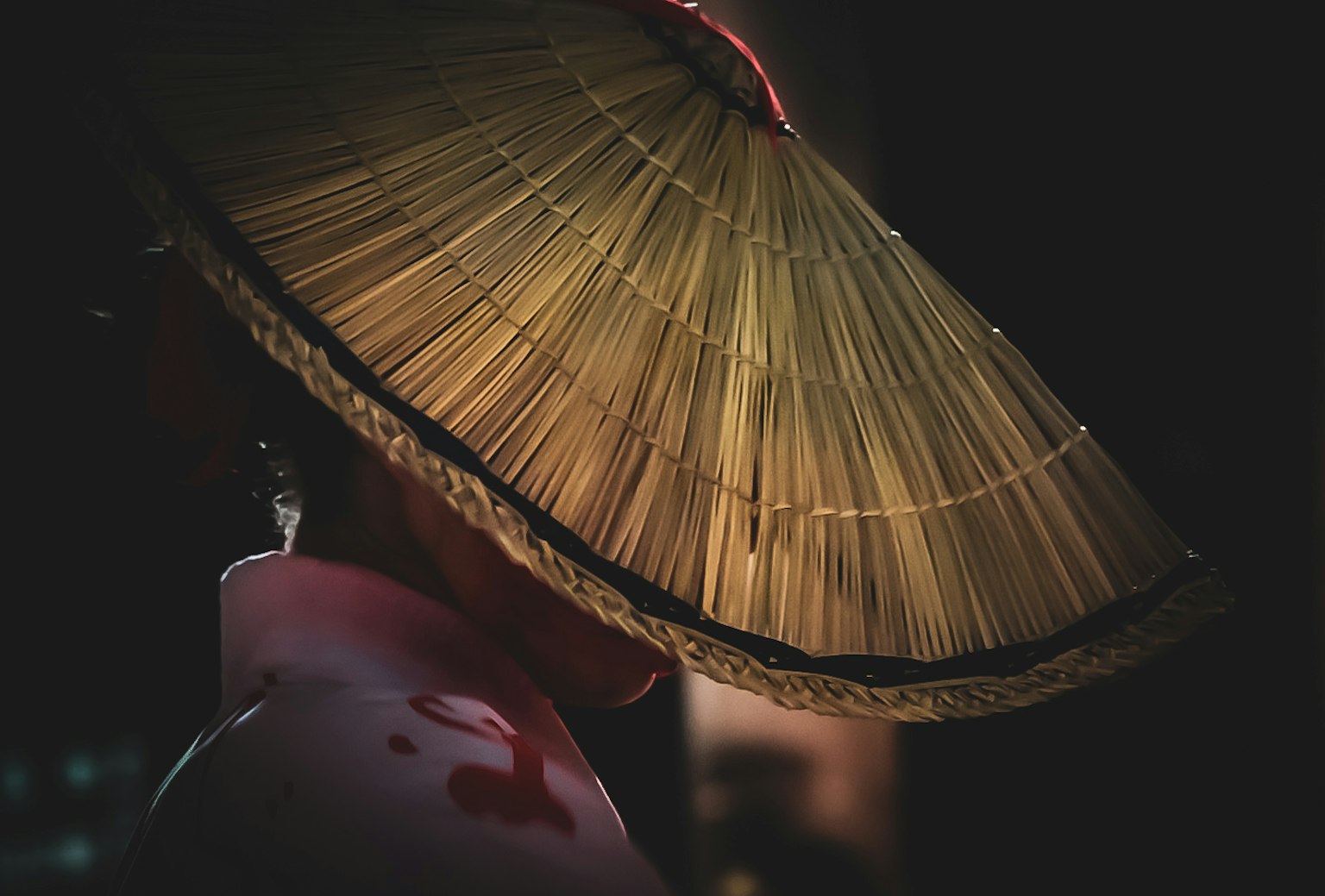 Silhouette di una donna che indossa un cappello di paglia tradizionale su uno sfondo scuro