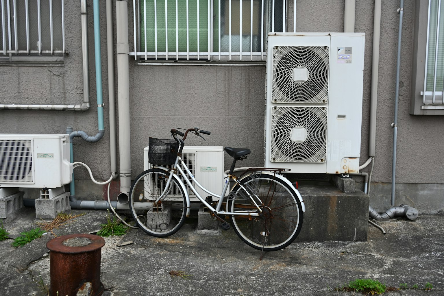 Bicicletta bianca accanto a unità di climatizzazione su un'esterno di un edificio