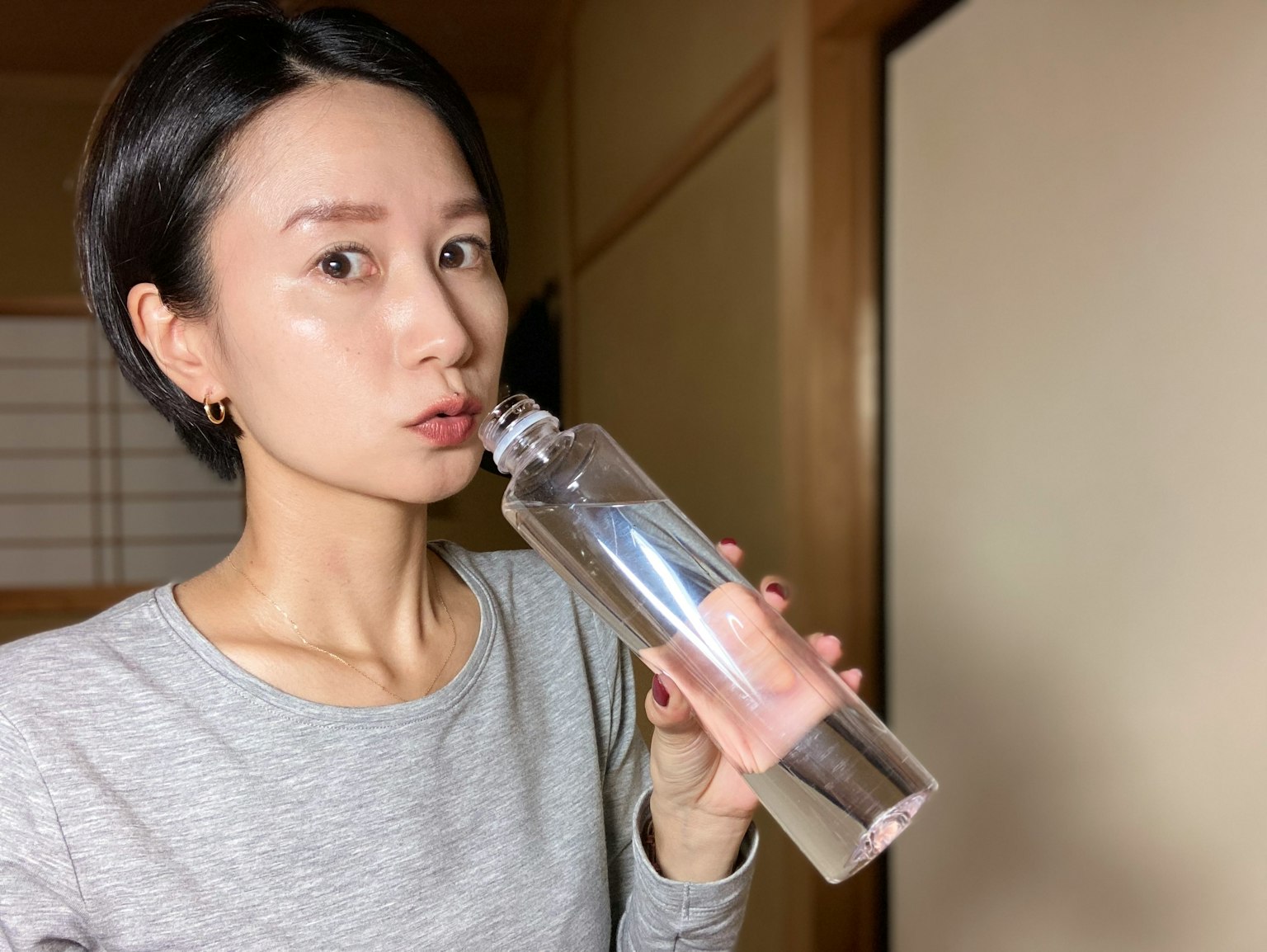 女性在舒適的室內環境中飲用透明水瓶中的水