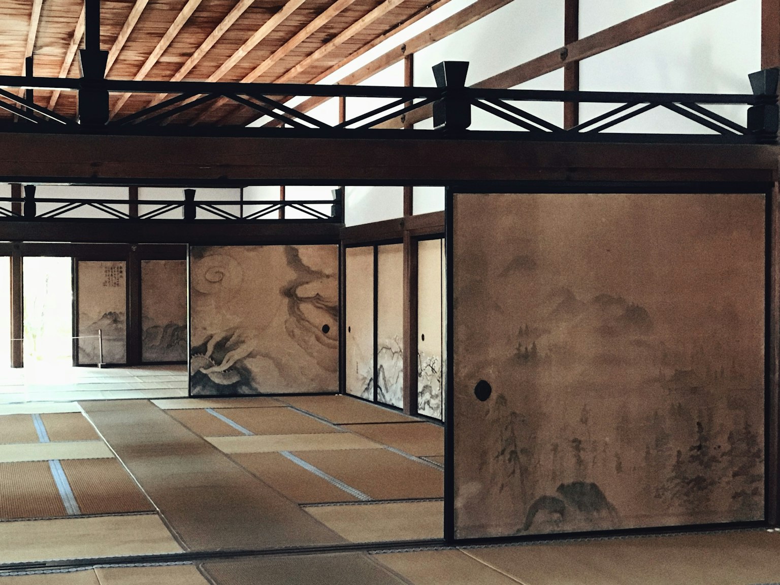 Interior of a traditional Japanese room featuring painted walls tatami flooring and wooden beams