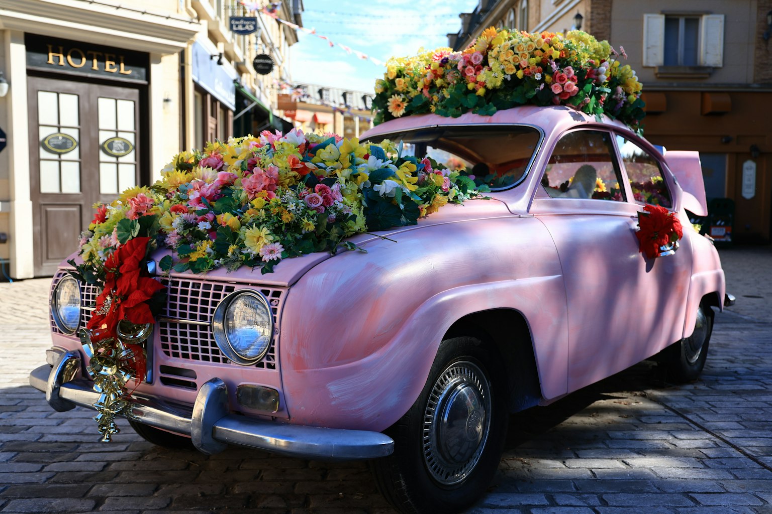 Une voiture rose ornée de fleurs garée dans une rue de la ville