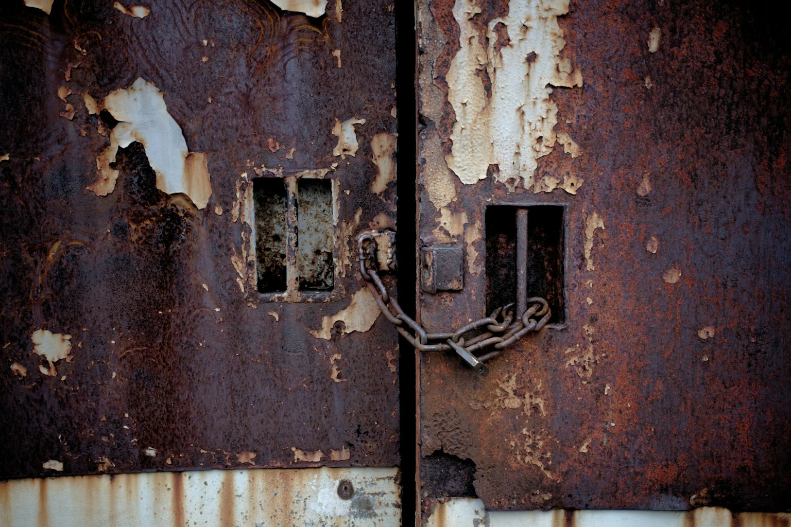Puertas metálicas oxidadas con cadena y aberturas