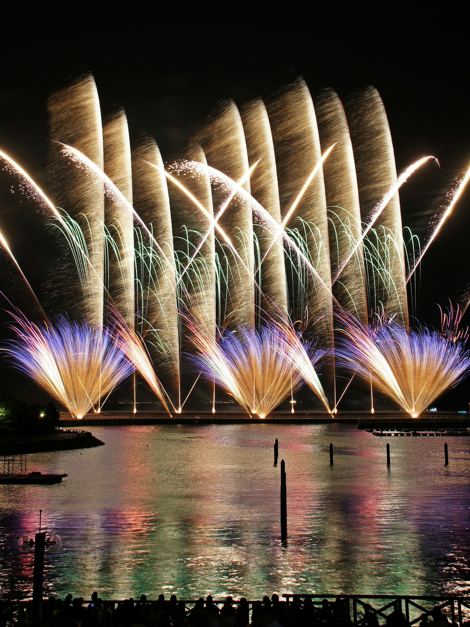 Vibrant fireworks display illuminating the night sky with colorful reflections on the water
