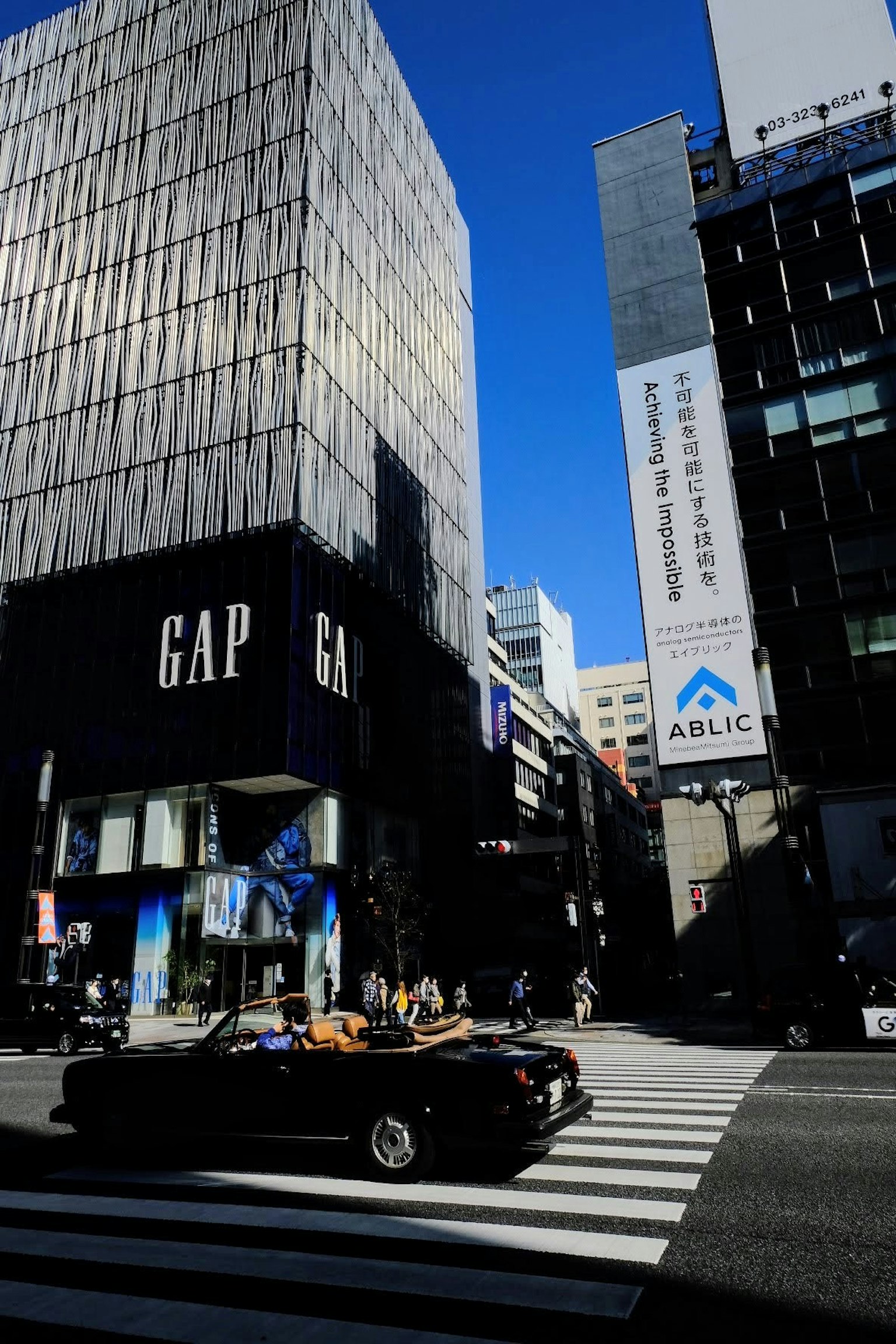 在蓝天之下，GAP商店和一辆车穿过交叉路口