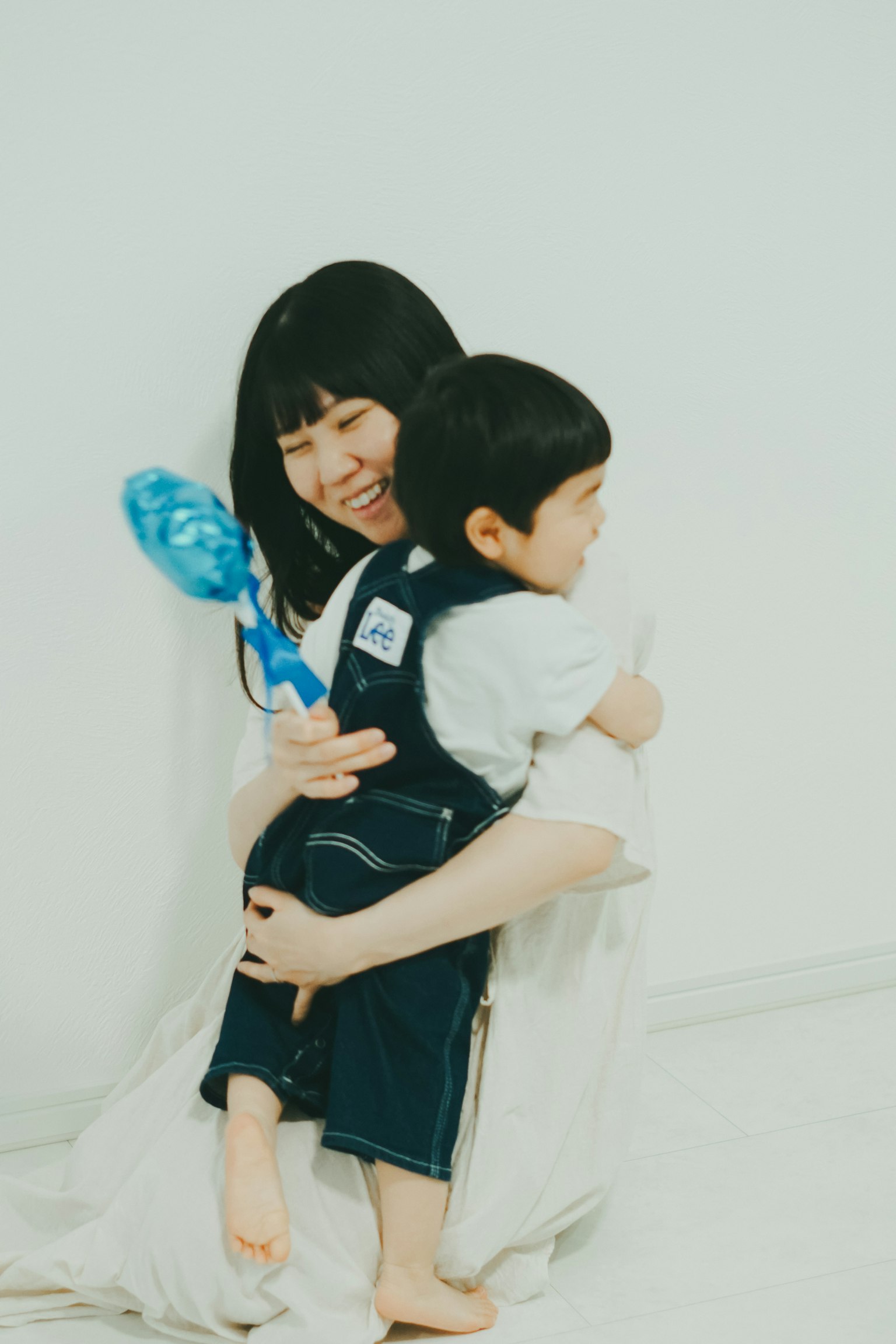 ผู้หญิงยิ้มกอดเด็กอยู่หน้าพื้นหลังสีขาว