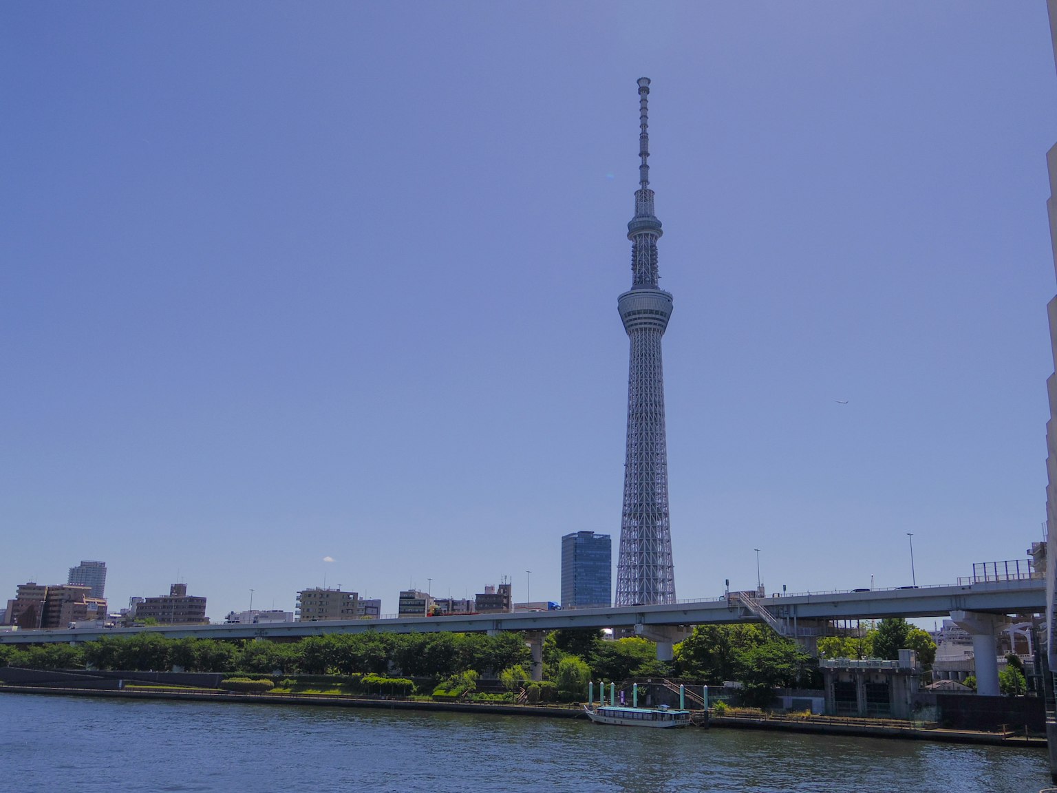 Tokyo Skytree, der über dem Fluss unter einem klaren blauen Himmel ragt