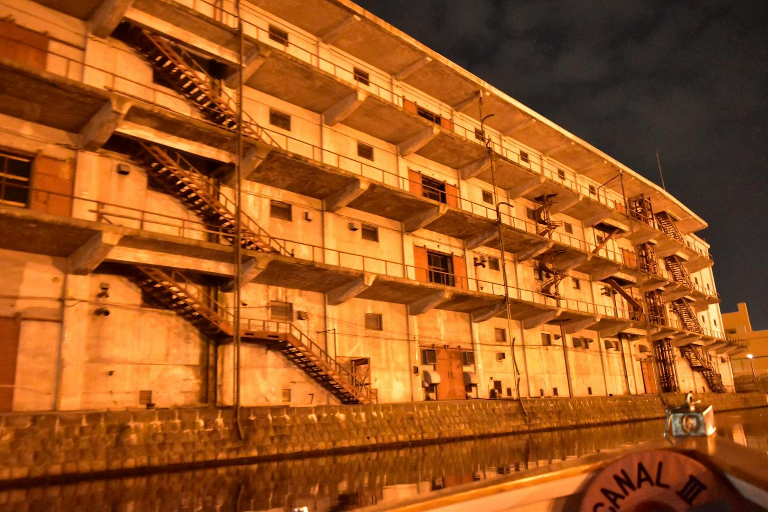 Vista esterna di un vecchio edificio residenziale di notte con scale metalliche e finestre