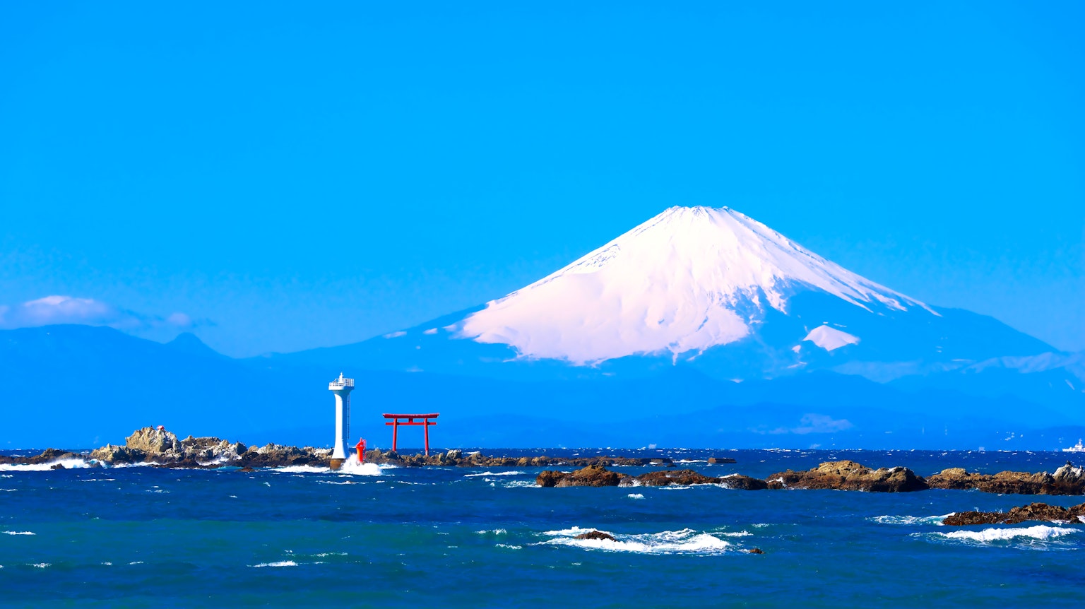 Scenic view of Mount Fuji with a blue sky and ocean lighthouse and torii gate