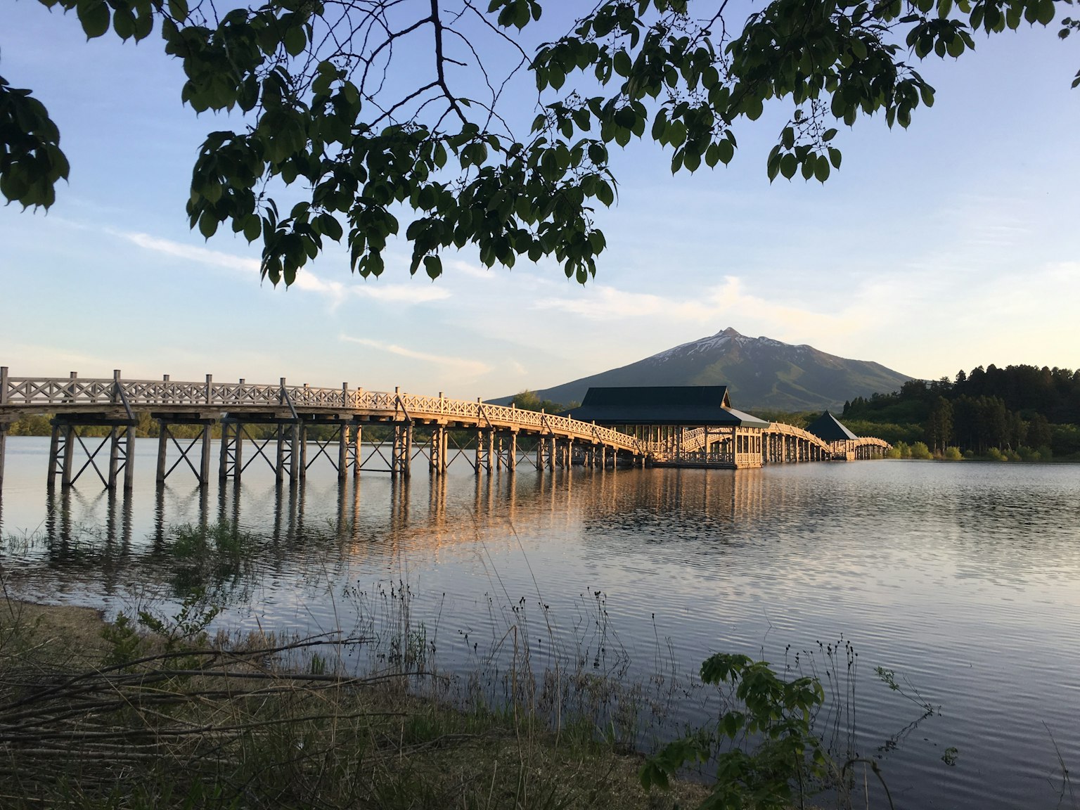 สะพานไม้ข้ามทะเลสาบพร้อมภูเขาอยู่เบื้องหลัง