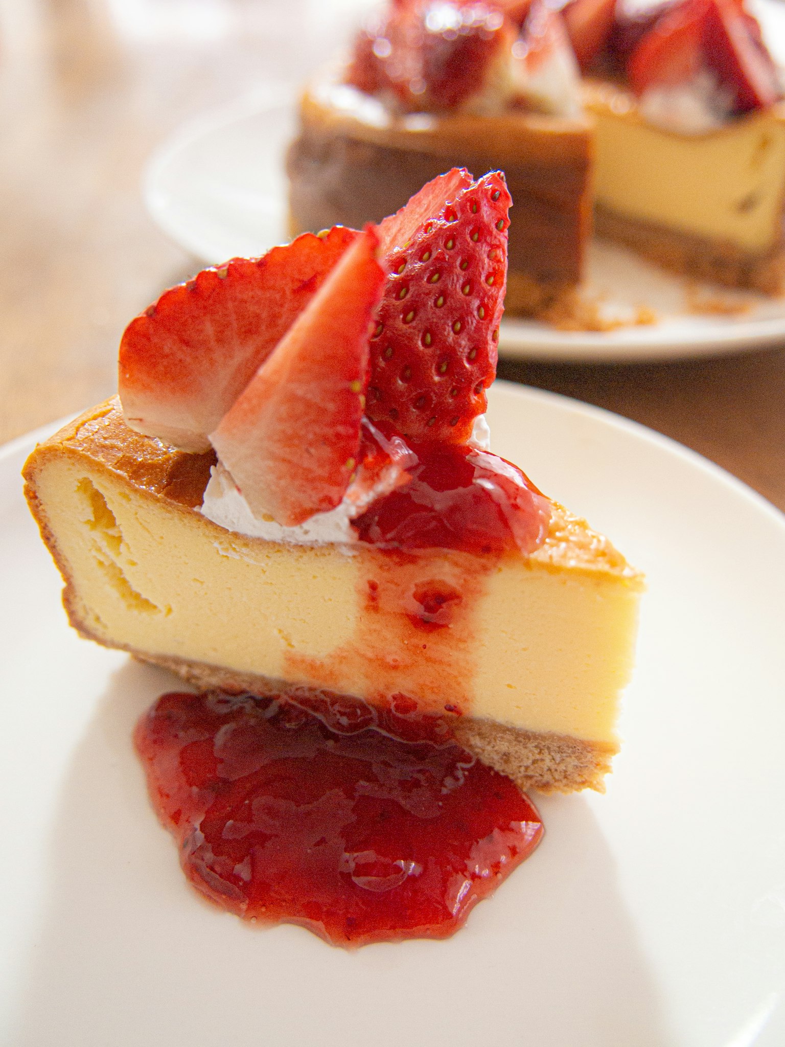 Stück Käsekuchen mit Erdbeersauce und frischen Erdbeeren