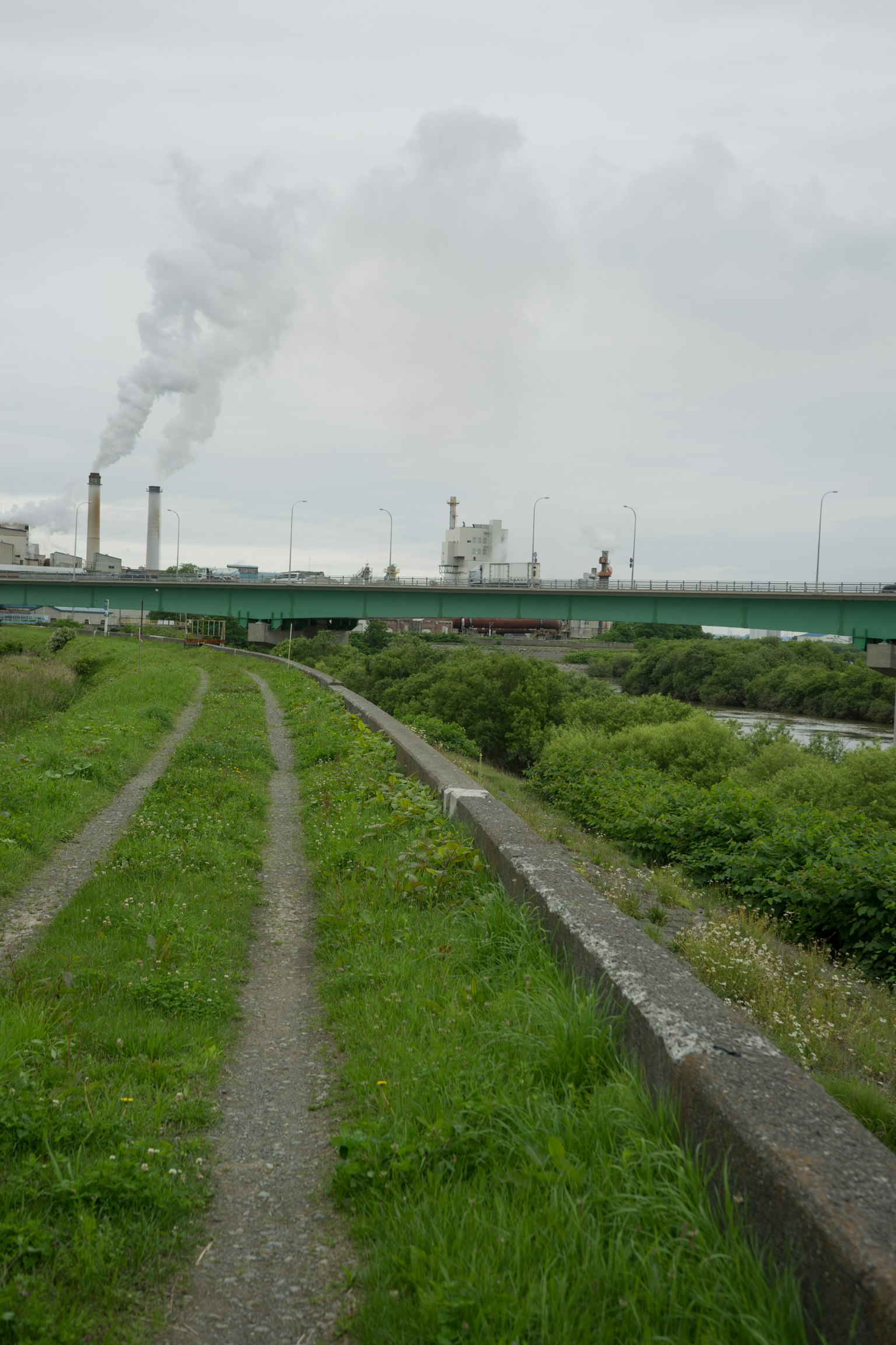 Landschaft mit Industrie-Schornsteinen und grünen Wegen