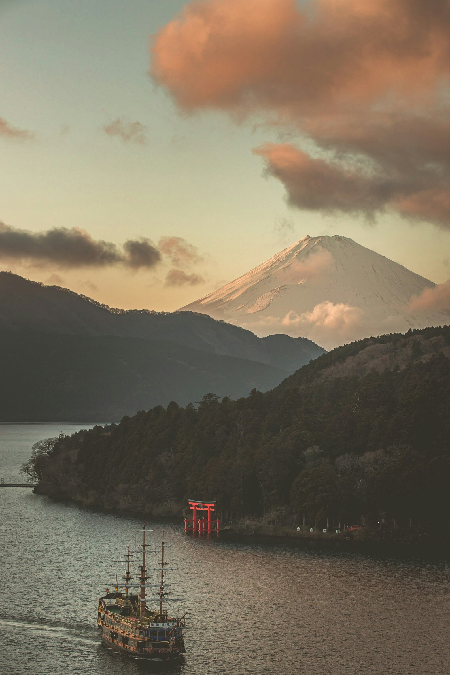 夕阳下的湖面船只与红色栈桥，远处群山