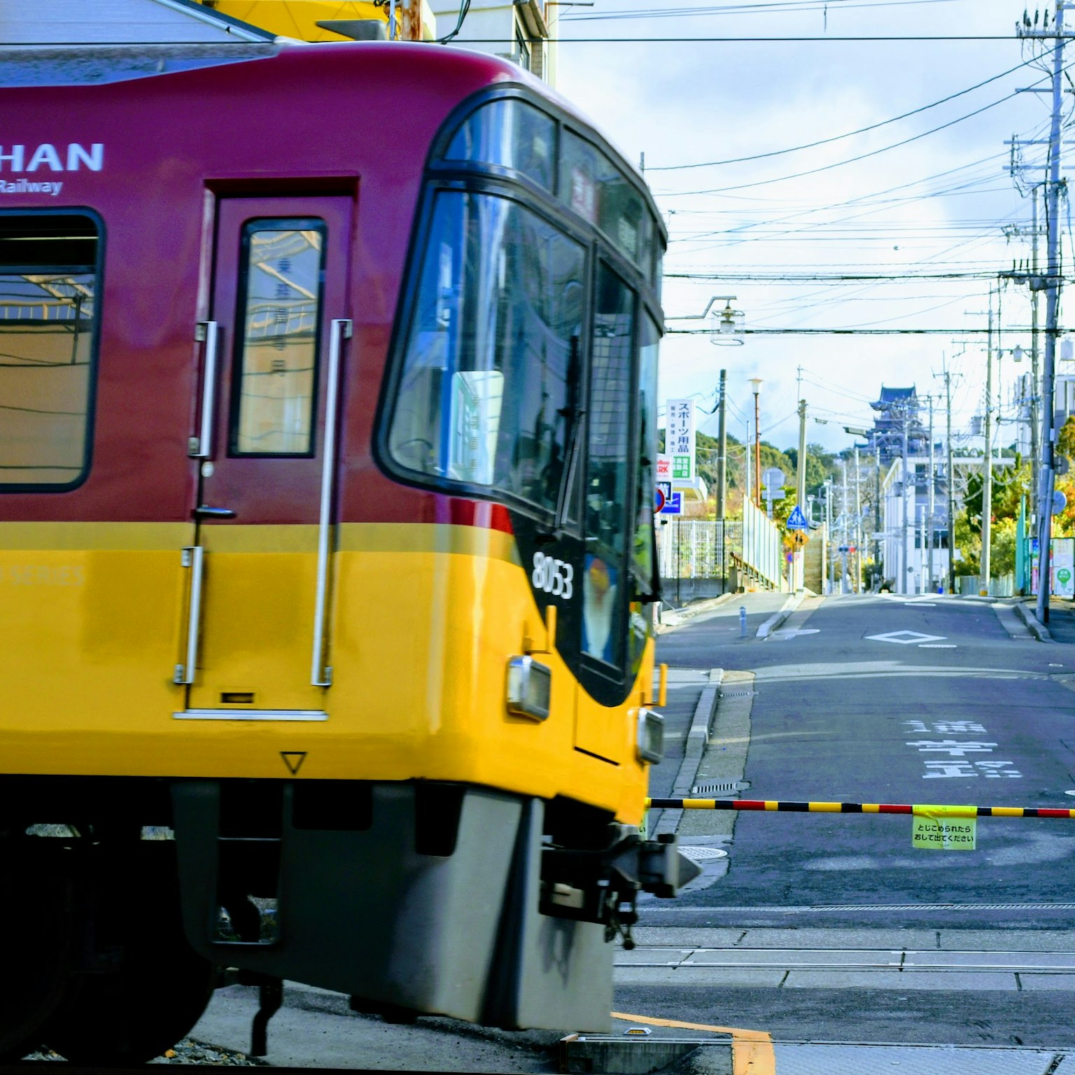 Un treno rosso e giallo fermo a un passaggio a livello