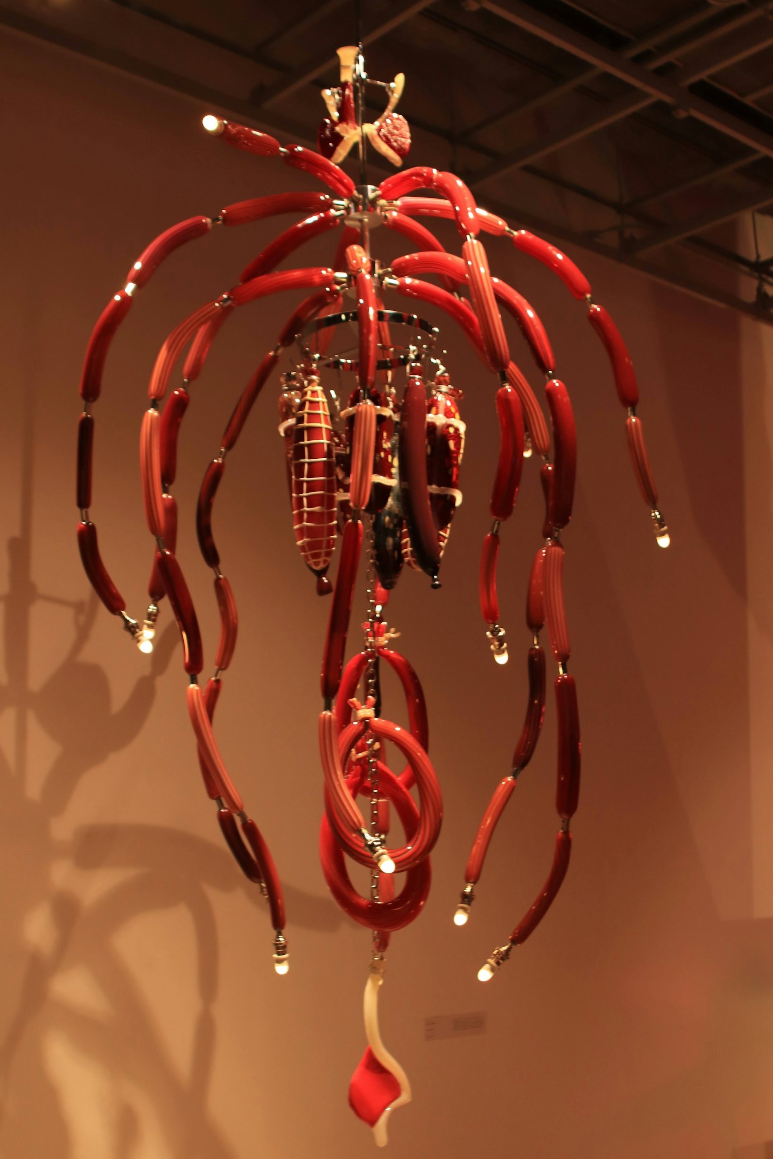 A hanging art piece with red tendrils and decorative elements