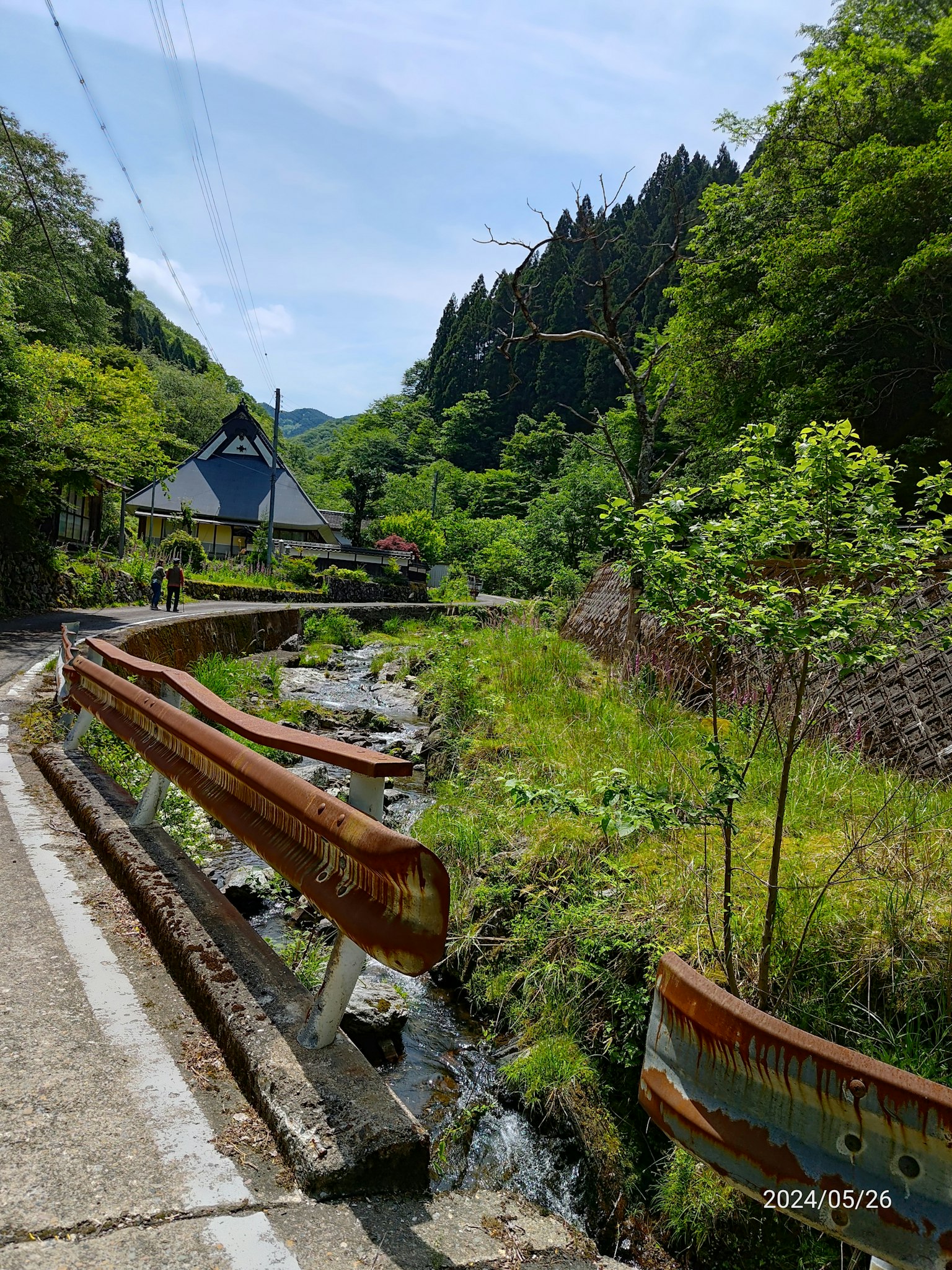 ทิวทัศน์ที่สวยงามของถนนในภูเขาพร้อมลำธารและบ้านแบบดั้งเดิม
