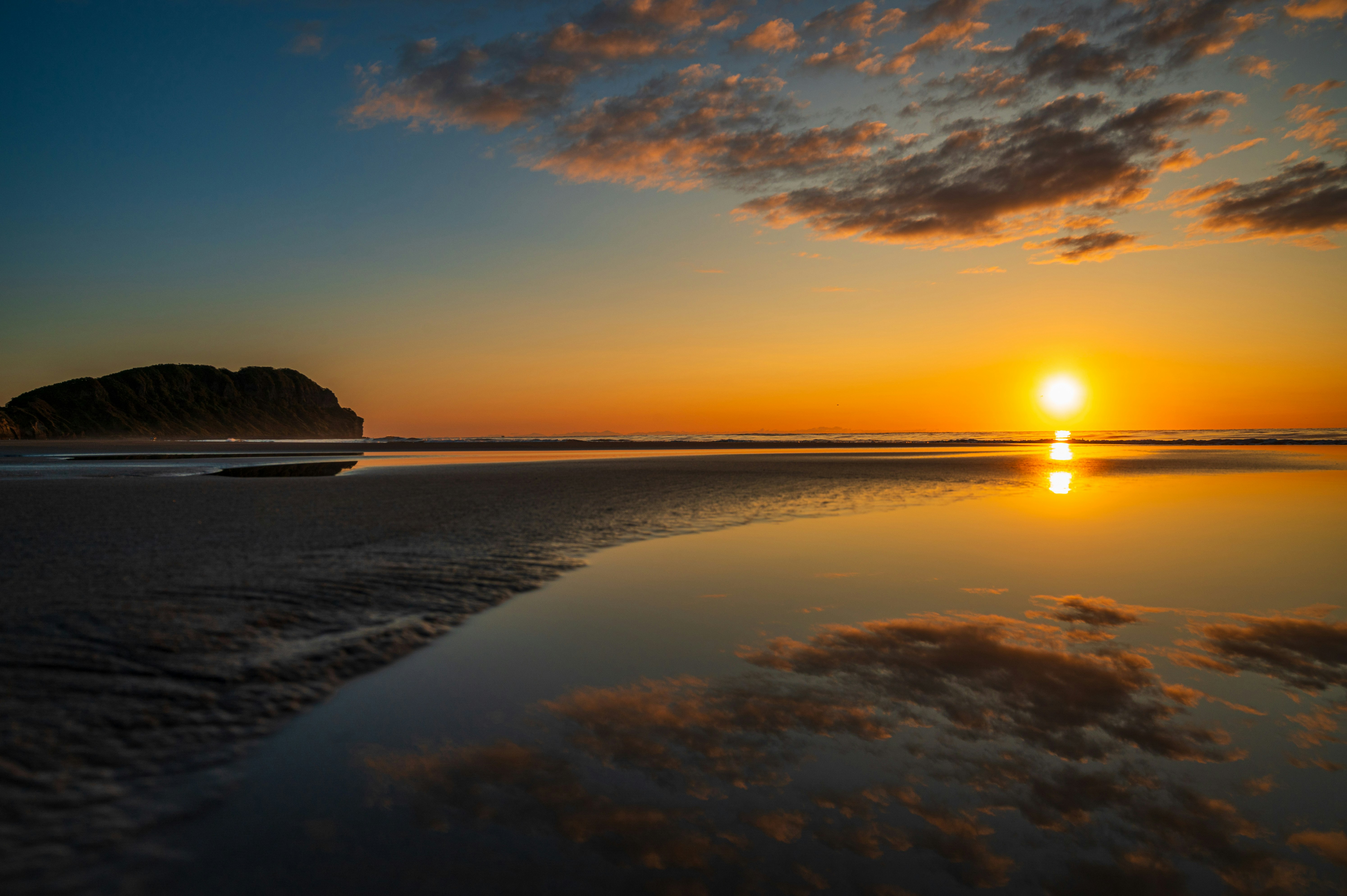 夕日に照らされた砂浜と水平線の海景
