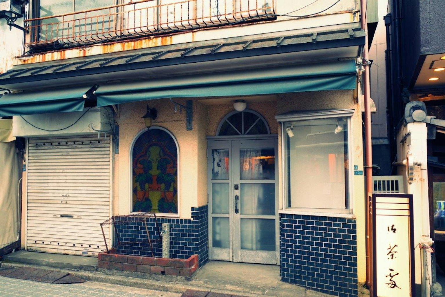 Façade d'un ancien bâtiment avec un auvent bleu et des fenêtres décoratives