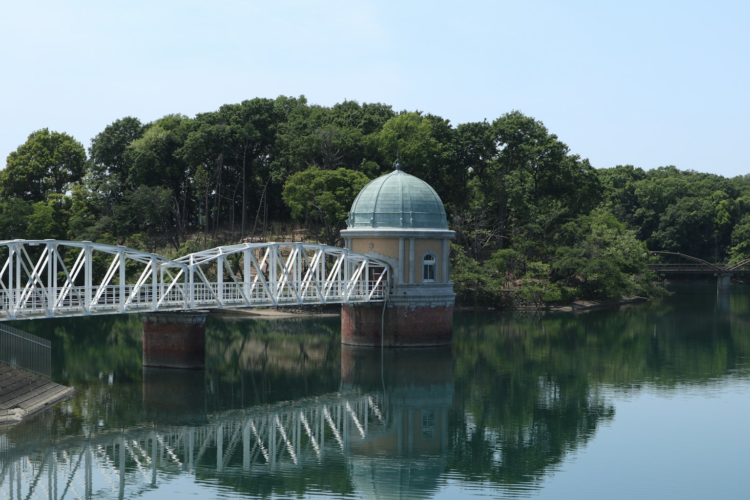 Vista panoramica di un piccolo edificio a cupola e un ponte bianco riflesso in acqua calma