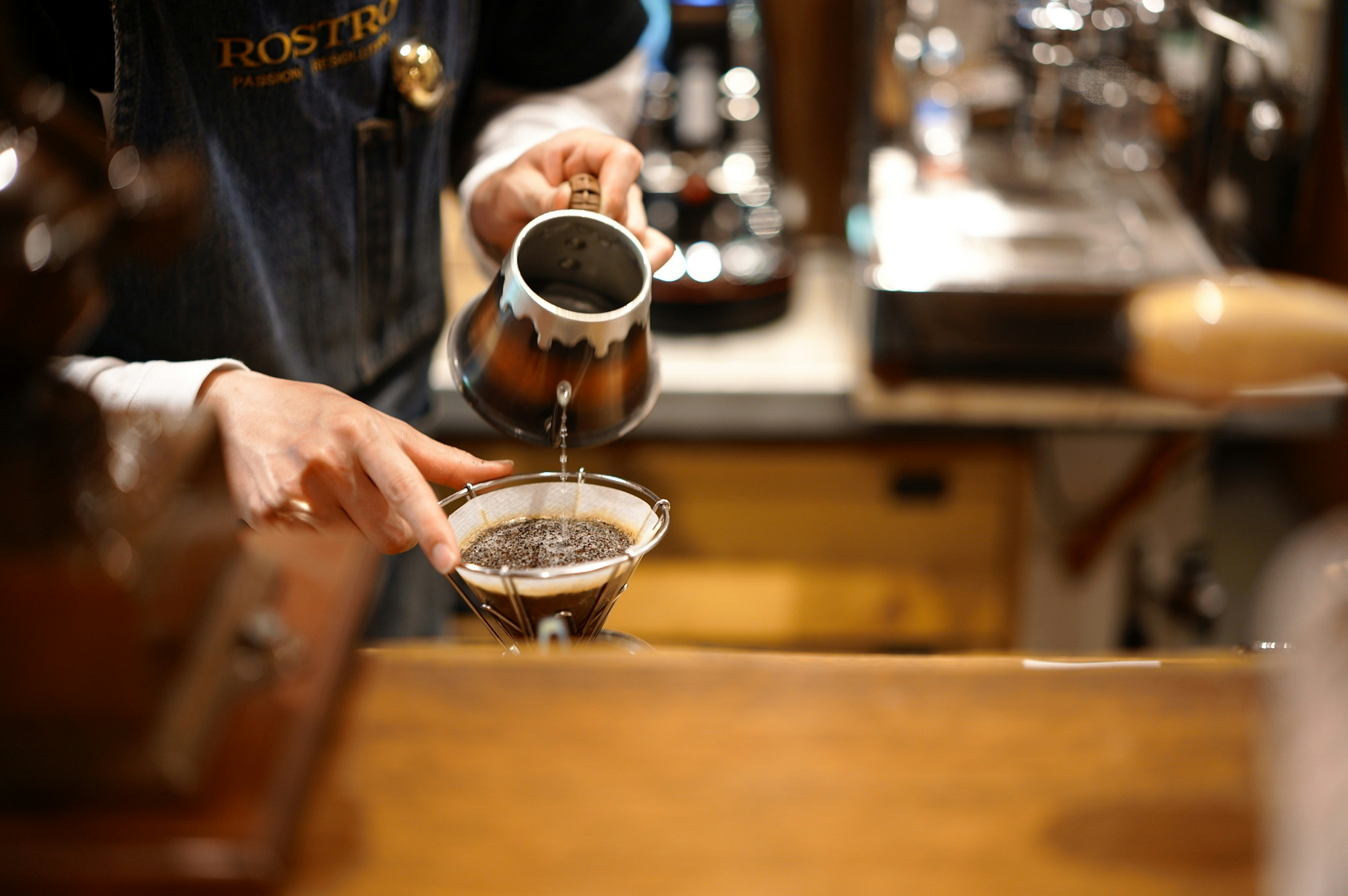 mani che versano il caffè su un filtro al bancone