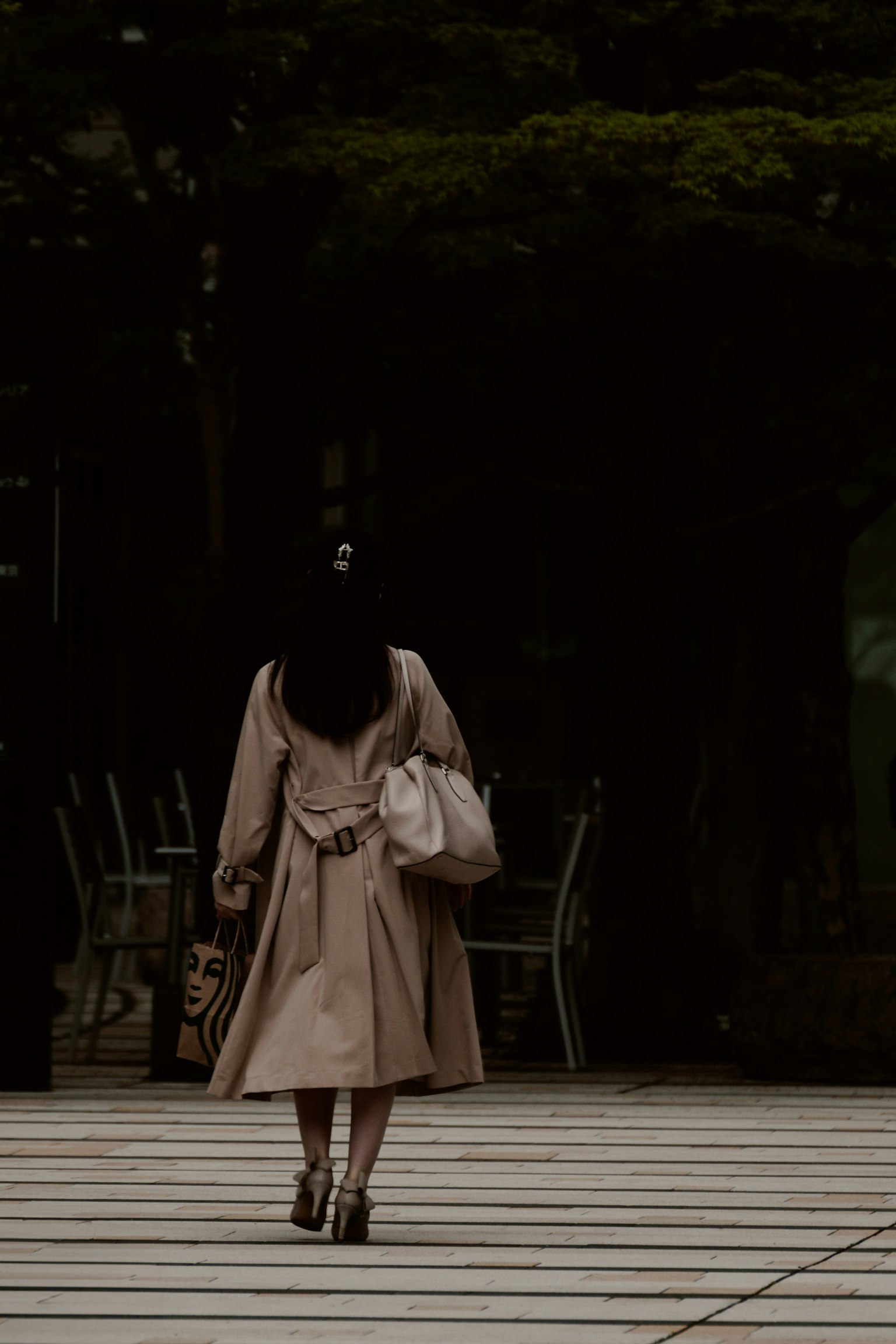 연한 베이지색 코트를 입은 여성이 뒤로 걷고 있다