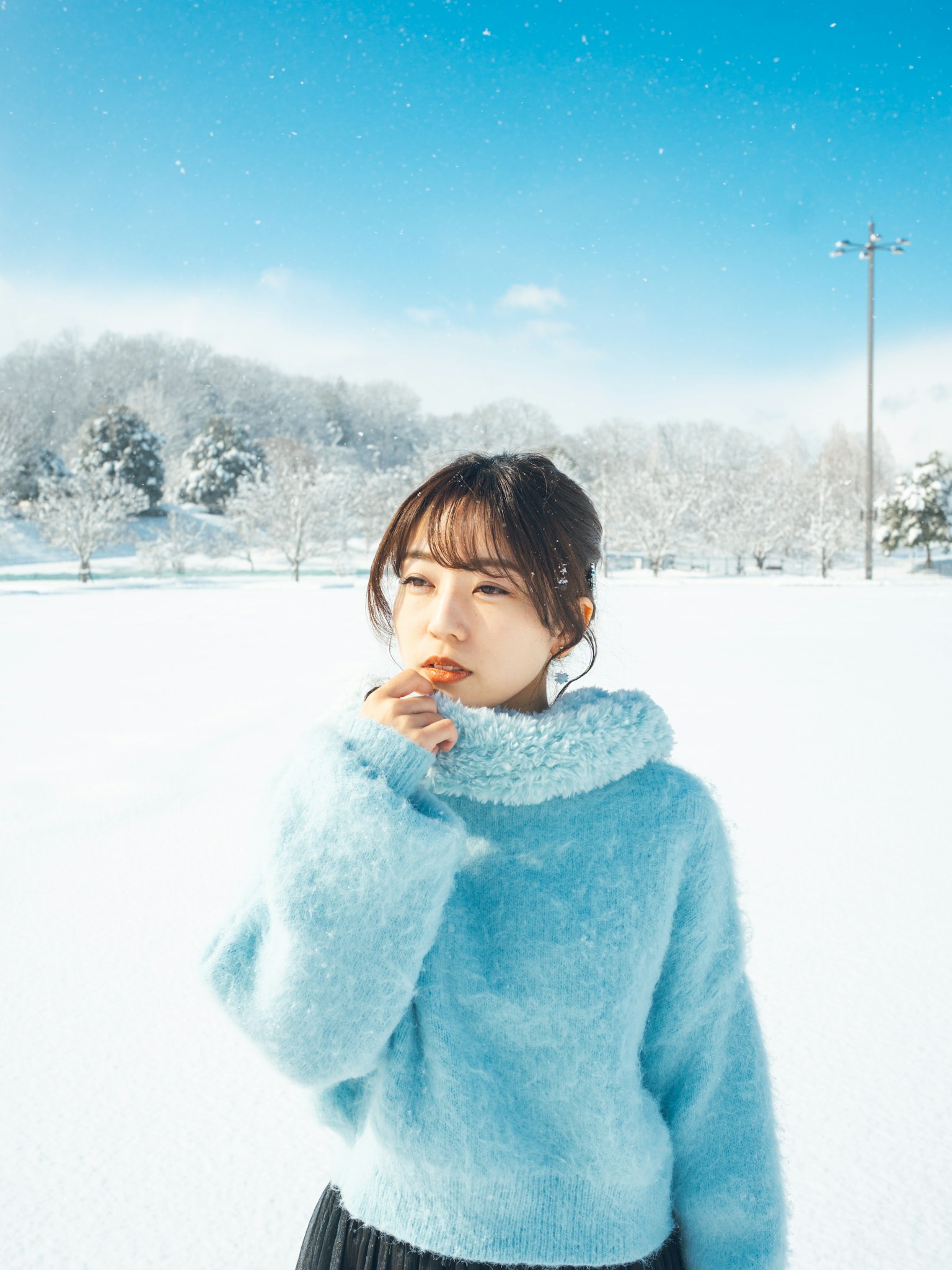 Une femme en pull bleu se tenant dans la neige