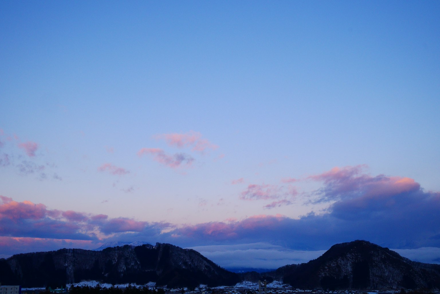 青い空とピンクの雲が広がる山の景色