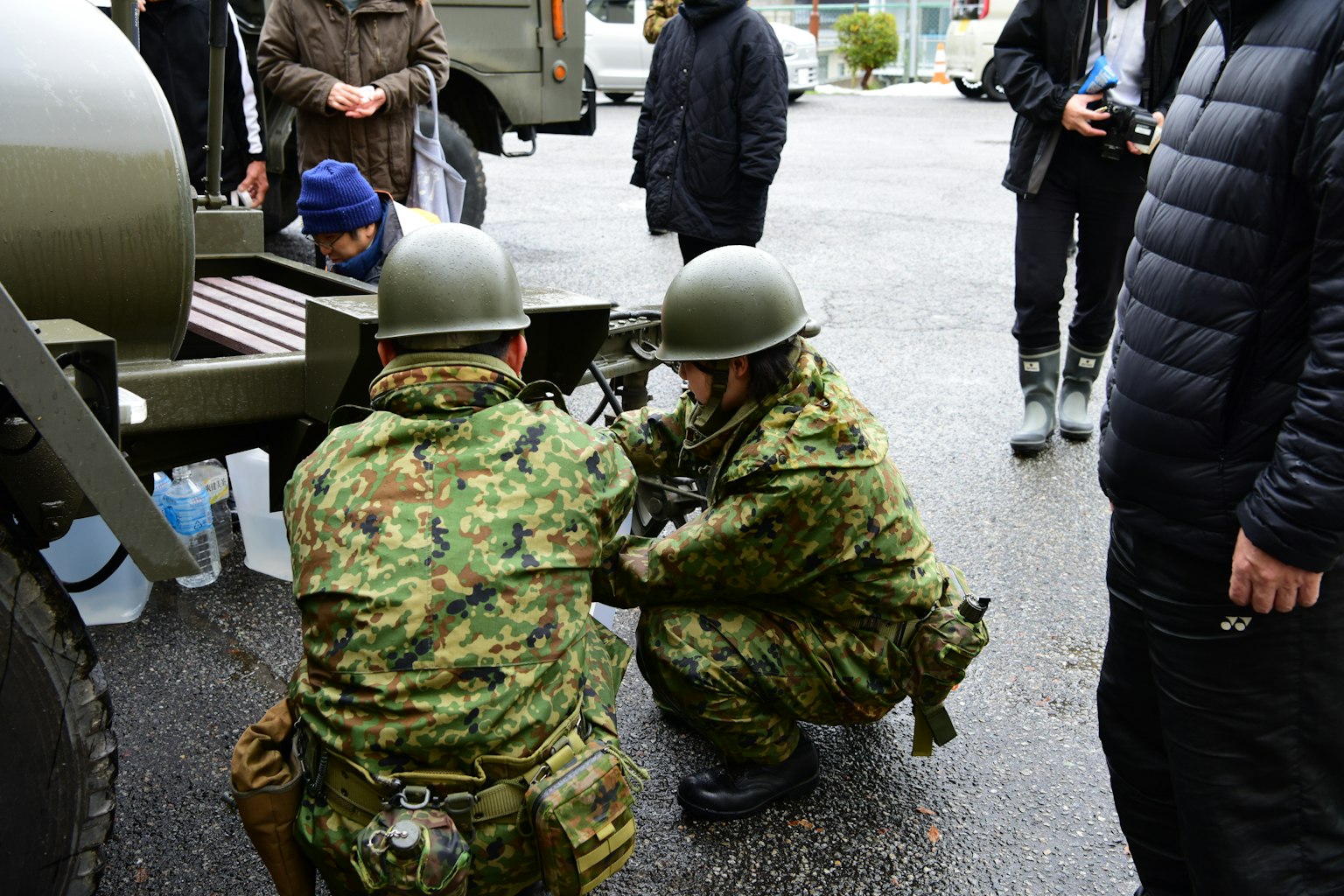 Two soldiers performing maintenance on a military vehicle