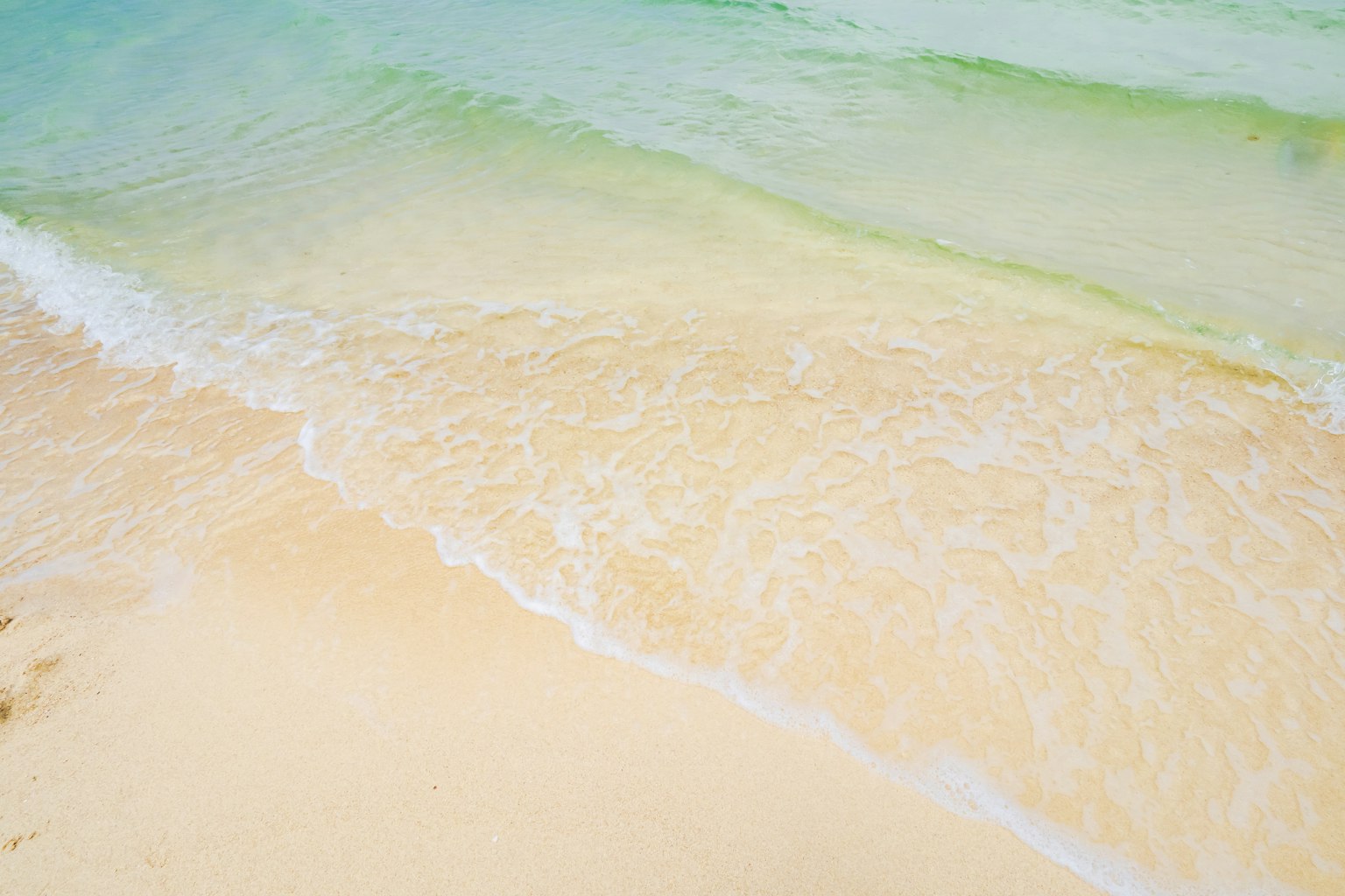 Vagues douces se brisant sur une plage de sable avec de l'eau claire