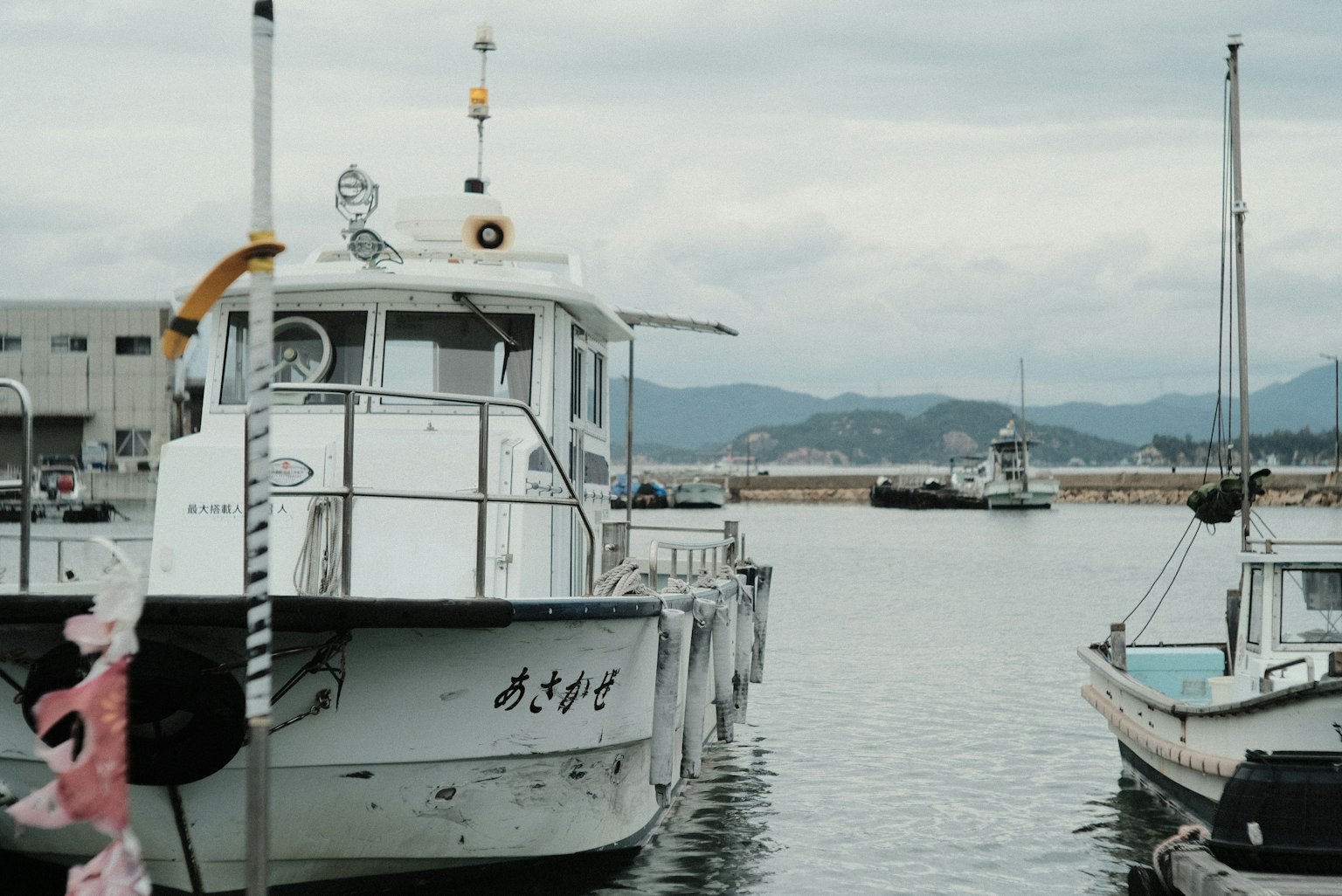 Bateau de pêche blanc amarré au port avec des montagnes en arrière-plan