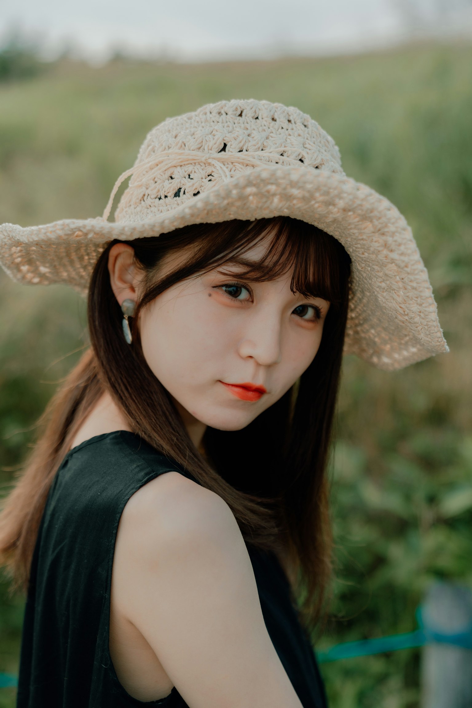 Chân dung phụ nữ đội mũ rơm trước nền xanh