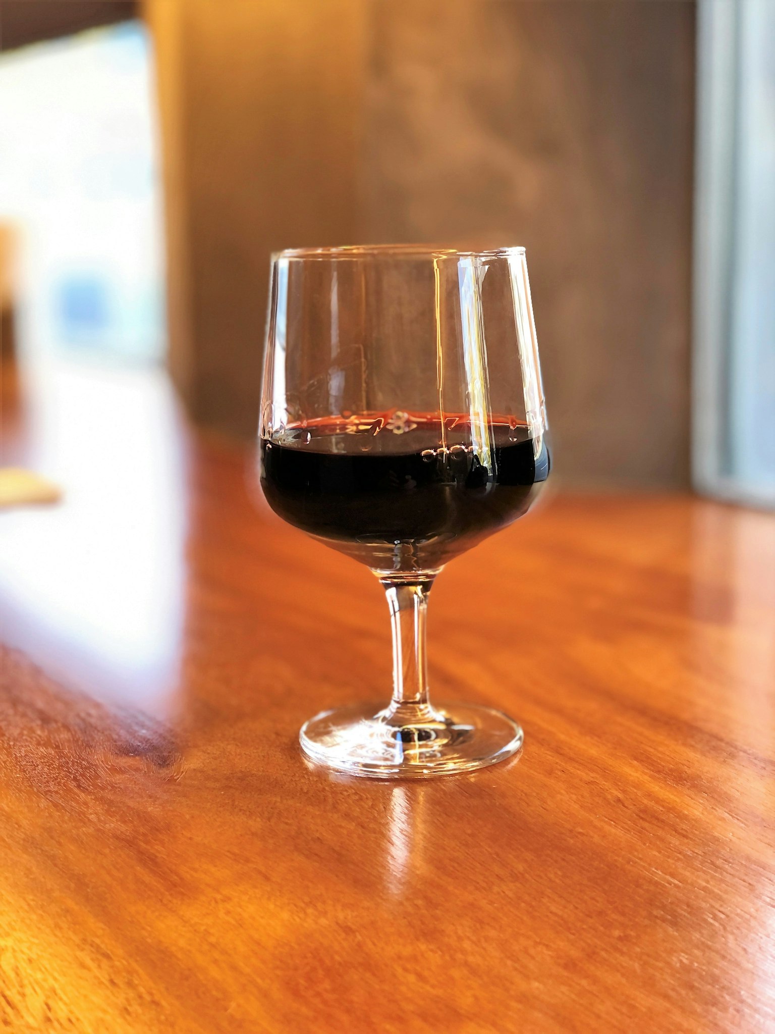 一个装满红酒的透明酒杯放在木桌上