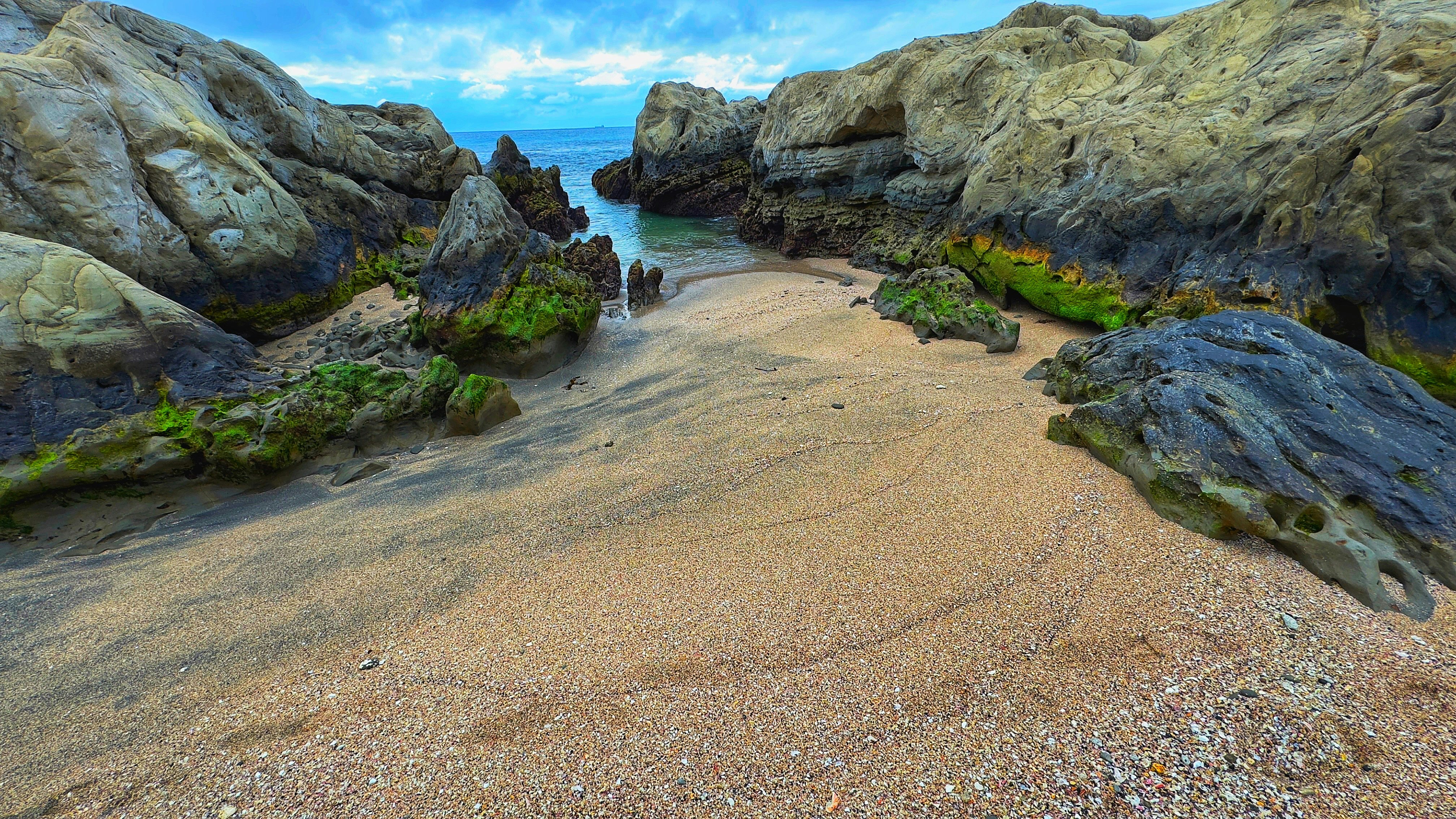 Cielo blu sopra una spiaggia di sabbia circondata da rocce
