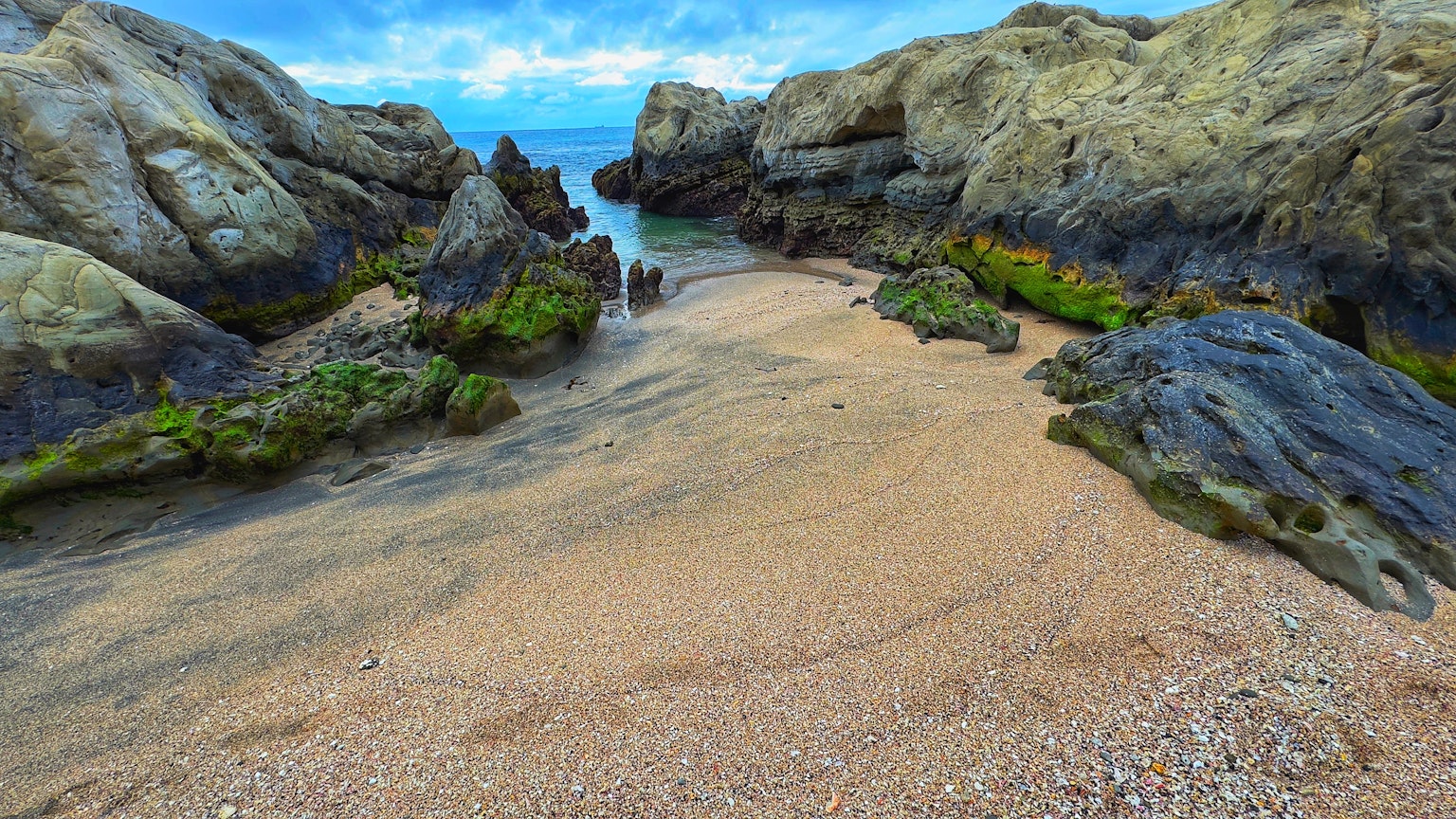 Beach scene surrounded by rocks with sandy shore and blue sea