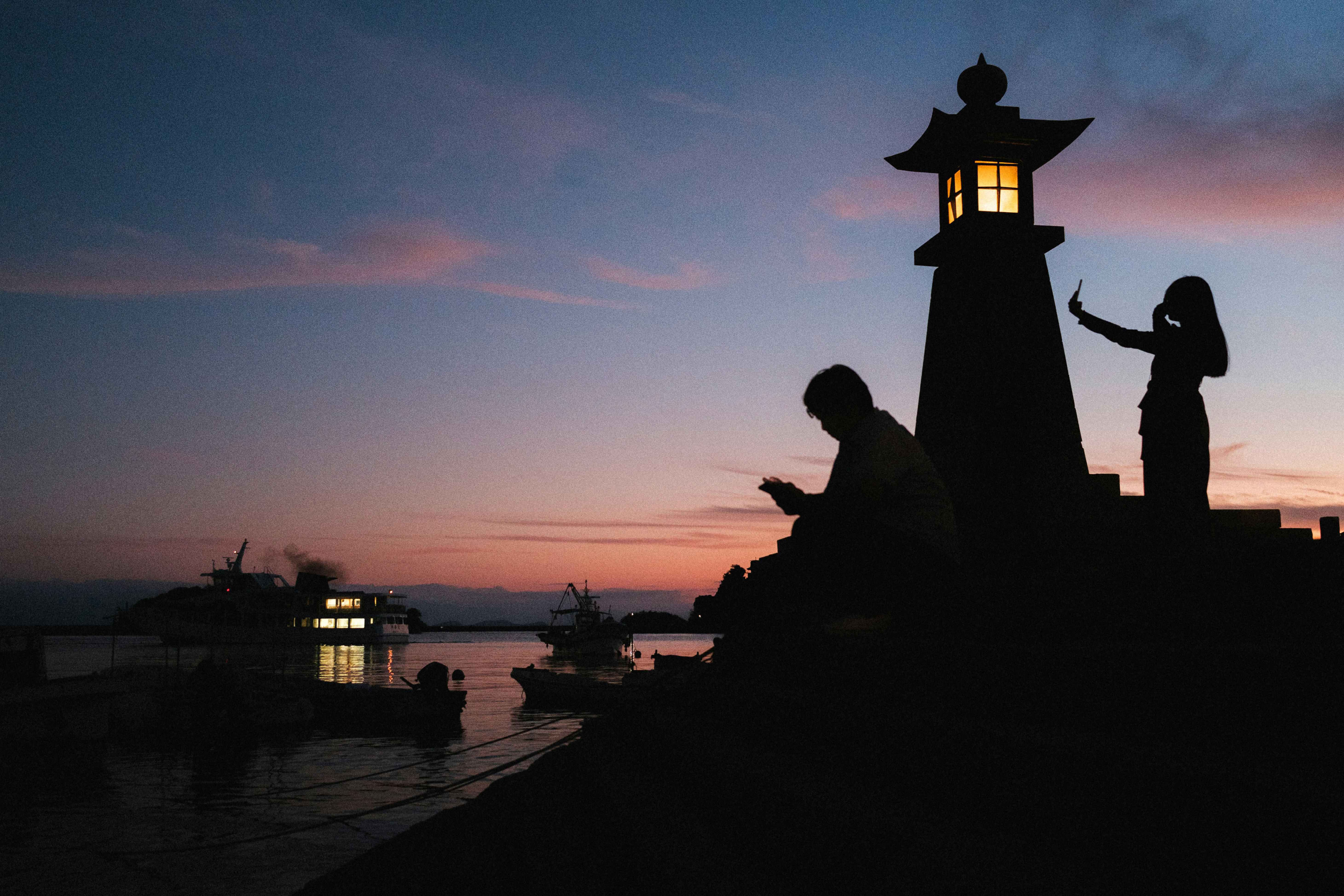 silhouettes d’un phare et d’une promenade en bord de mer au crépuscule