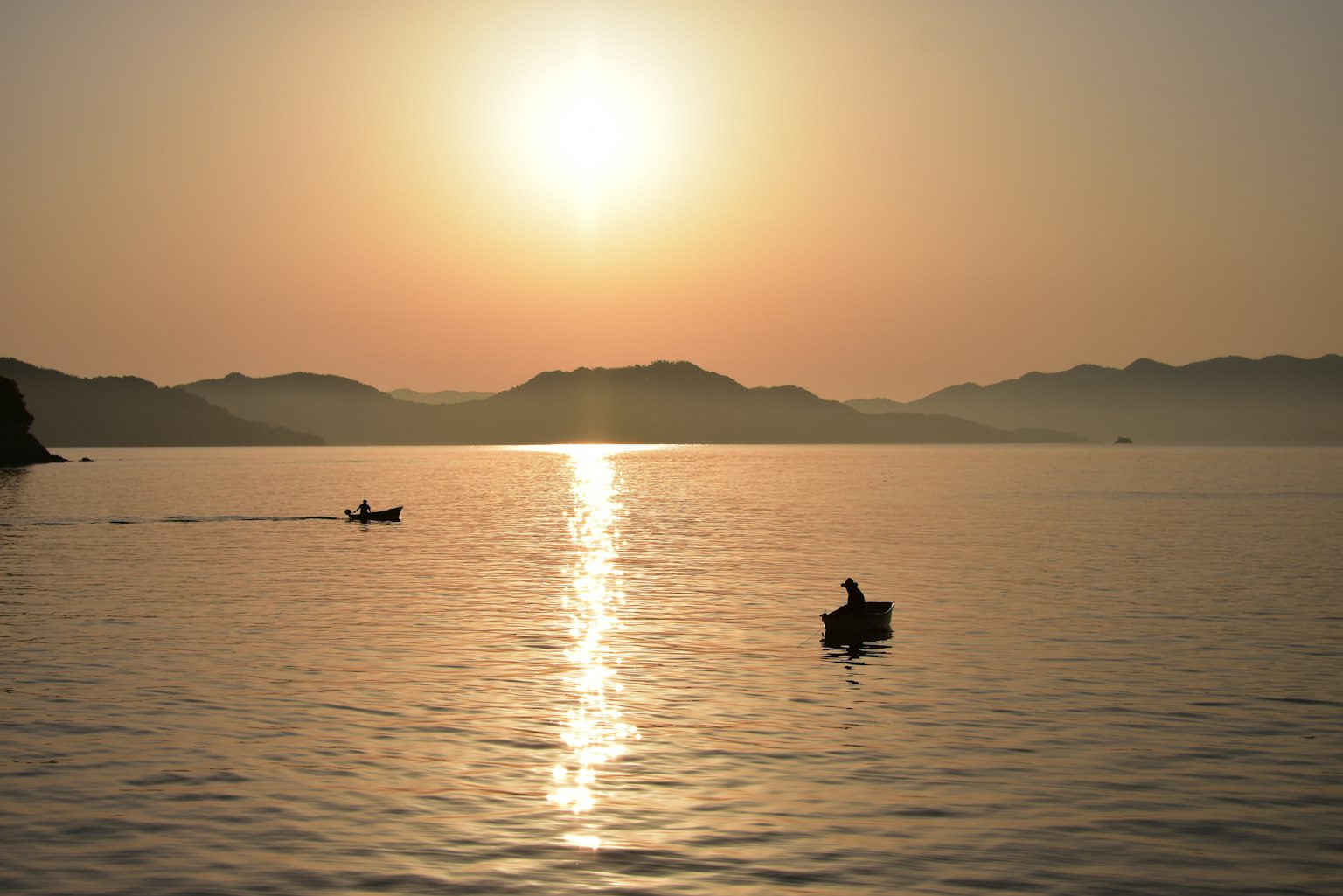 Deux bateaux pagayant sur un lac calme au coucher du soleil